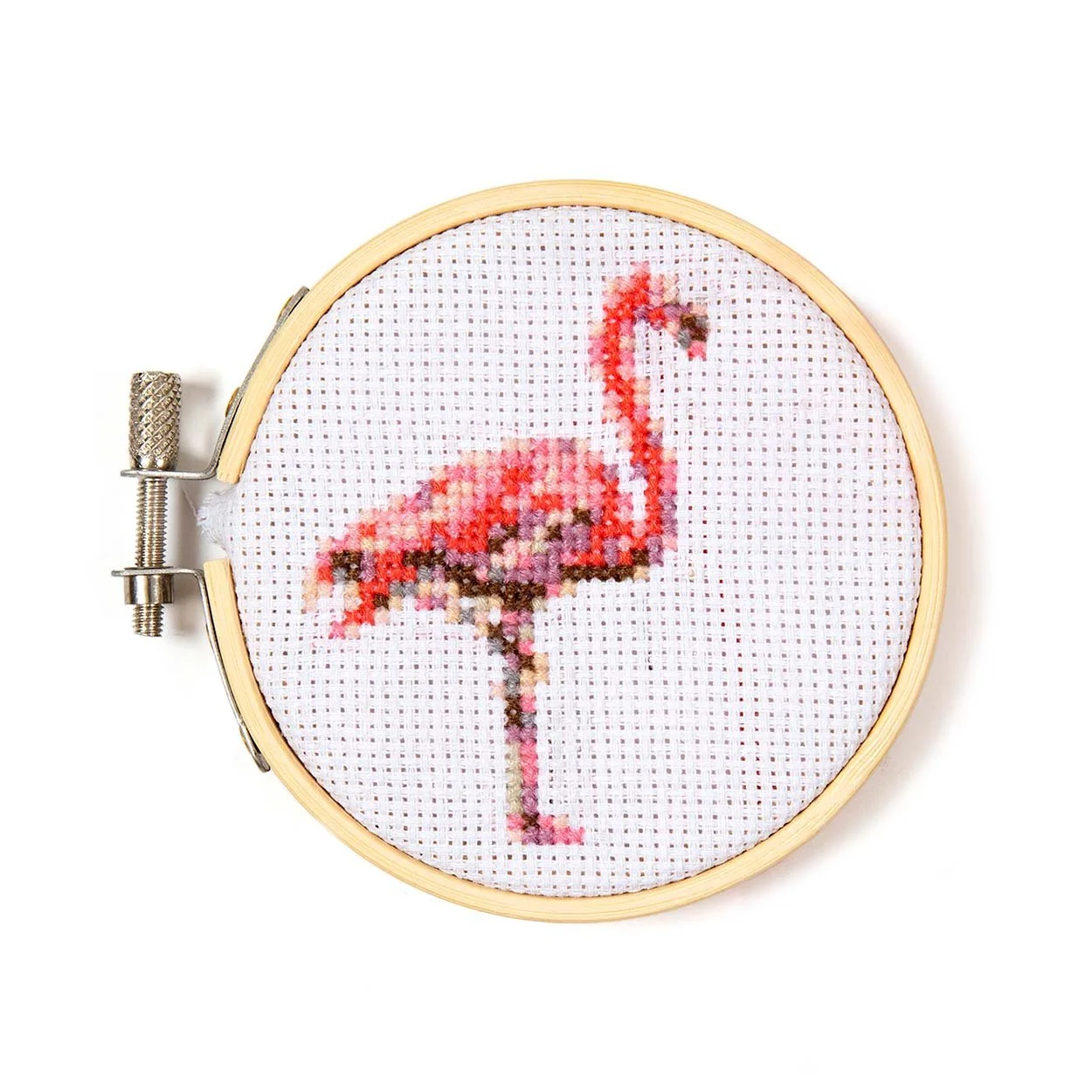 Completed mini flamingo cross stitch in a 3 inch bamboo hoop frame on white background