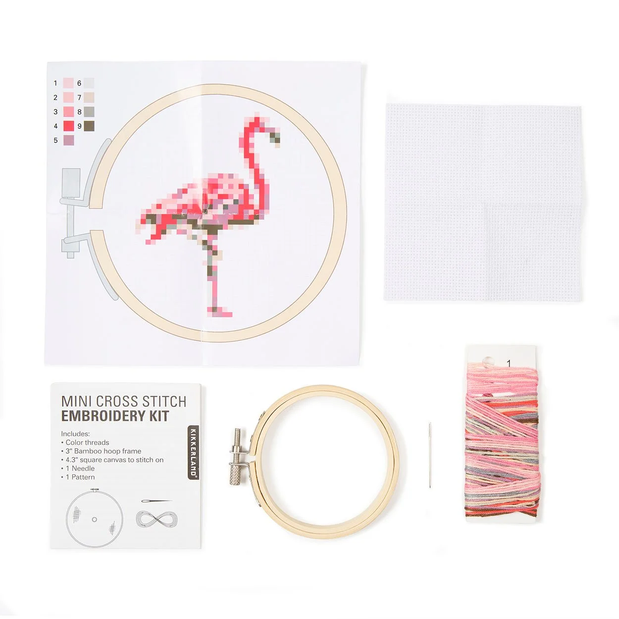 Mini flamingo cross stitch kit contents showing hoop, canvas, threads, needle, and pattern guide