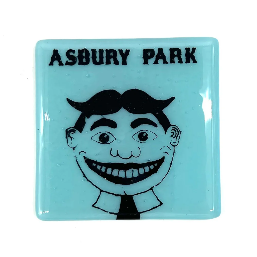 Overhead view of a robin's egg blue kiln-formed glass coaster with Tillie and Asbury Park text in black enamel