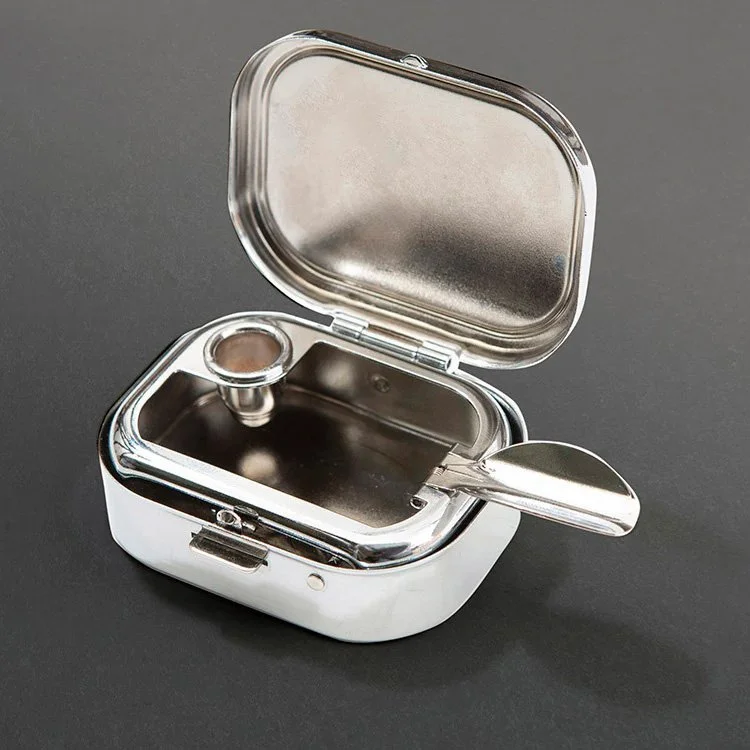 Open silver pocket ashtray showing interior stub holder and hinged lid on dark background