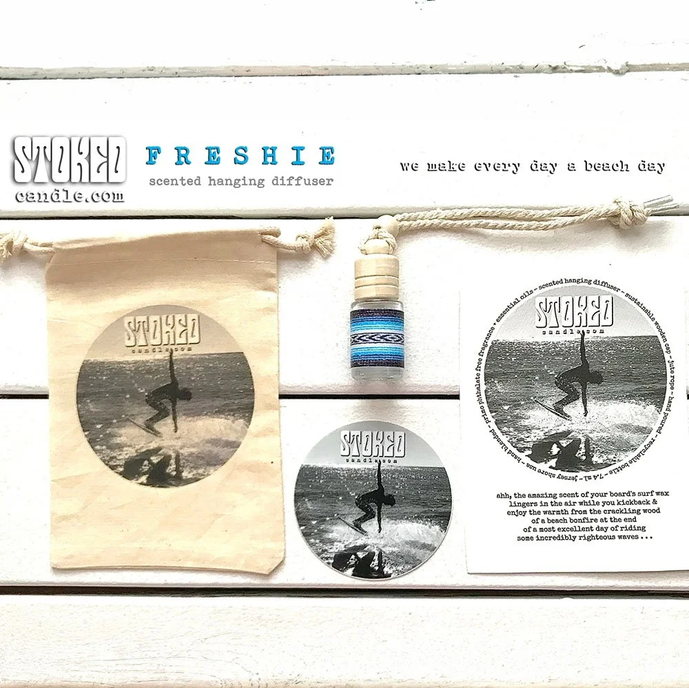 Stoked Freshie scented diffuser gift set flatlay showing glass bottle, cotton drawstring bag, logo sticker and care card on white background