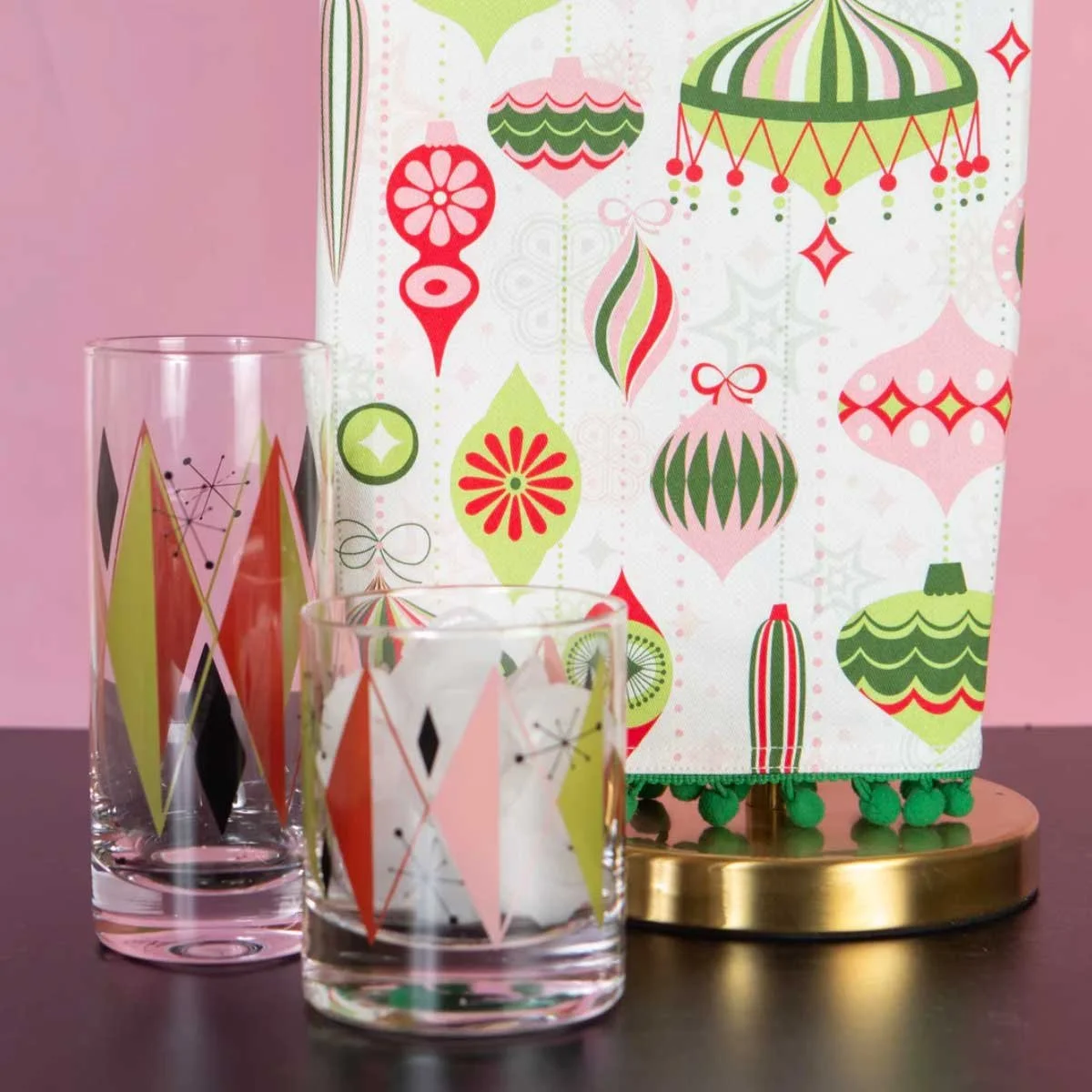 Mid-century atomic diamond highball and rocks glasses displayed with a retro bold print ornament gift bag on a gold tray
