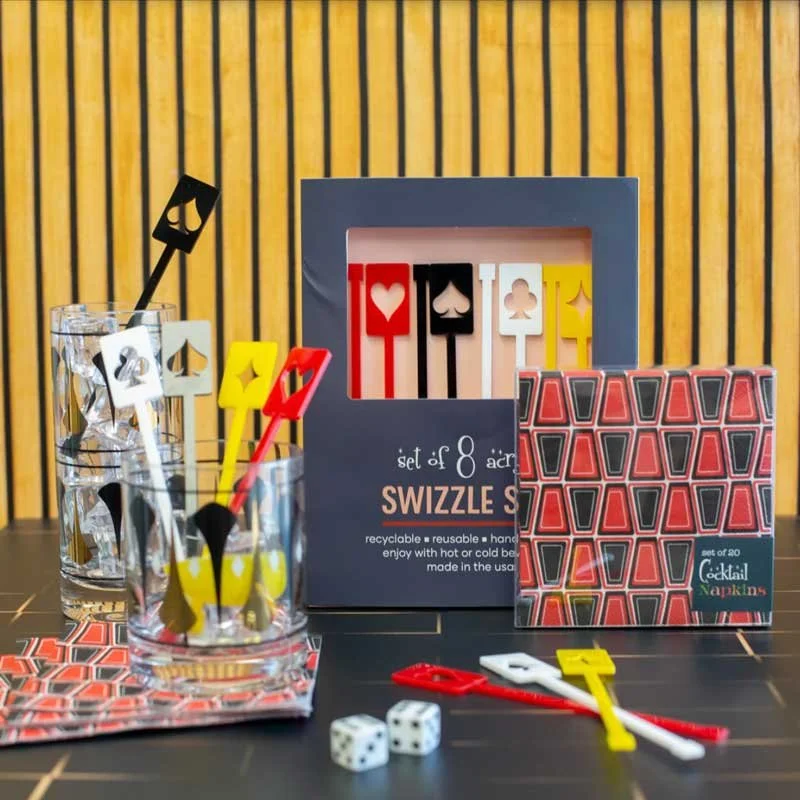 Red and black retro blocks cocktail napkins styled with playing card swizzle sticks, atomic glasses, and dice on a bar