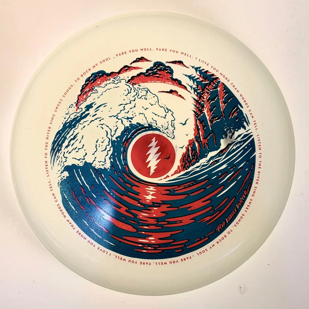 White glow frisbee with navy and red ocean wave design featuring a red lightning bolt circle and lyric text border