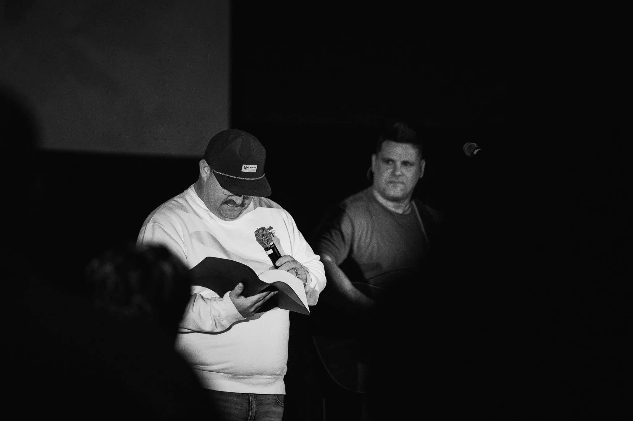 Three women engaged in conversation at an indoor event with musical instruments in the background.