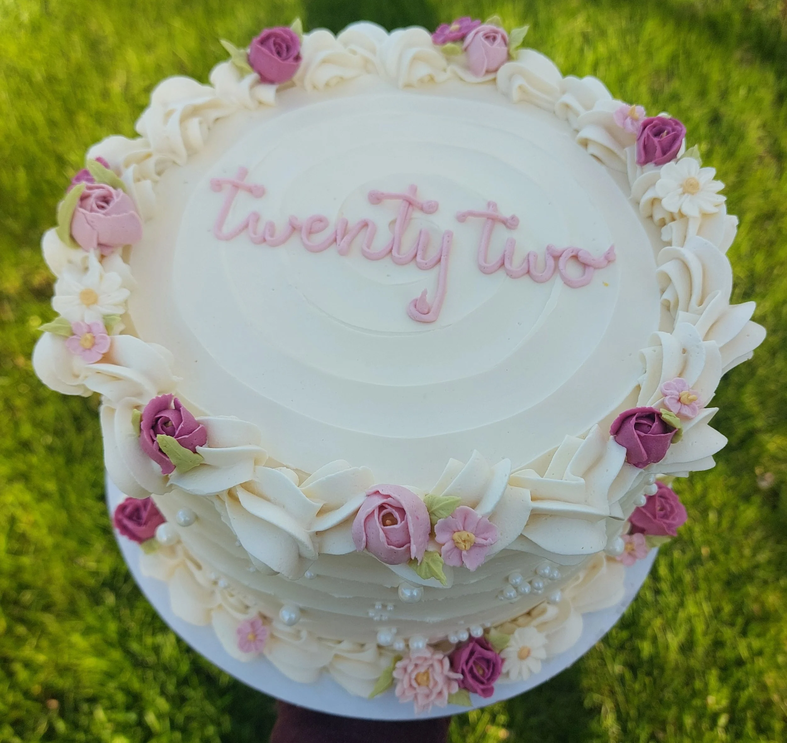 A custom cake decorated with pink and purple flowers and white pearls