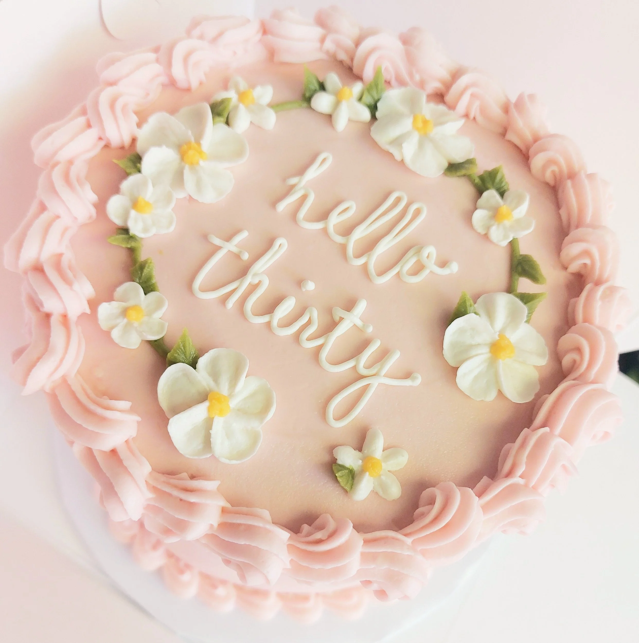 Classic pink birthday cake with florals and piping