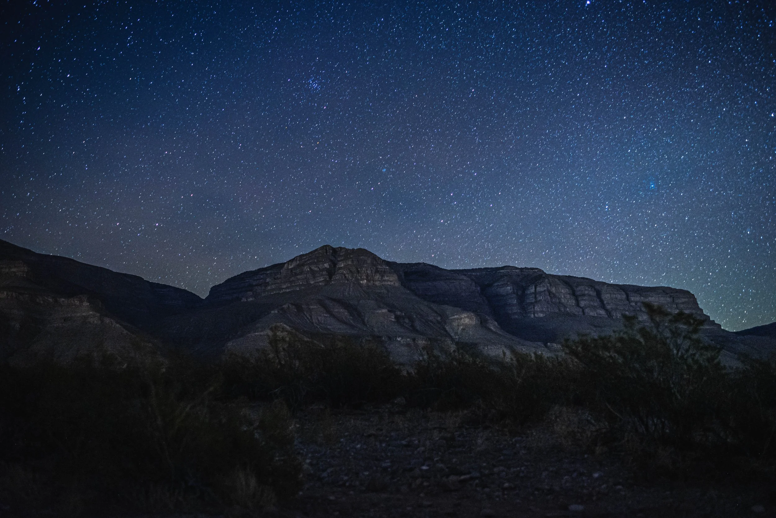 Nighttime mountain landscape with a clear, star-filled sky.