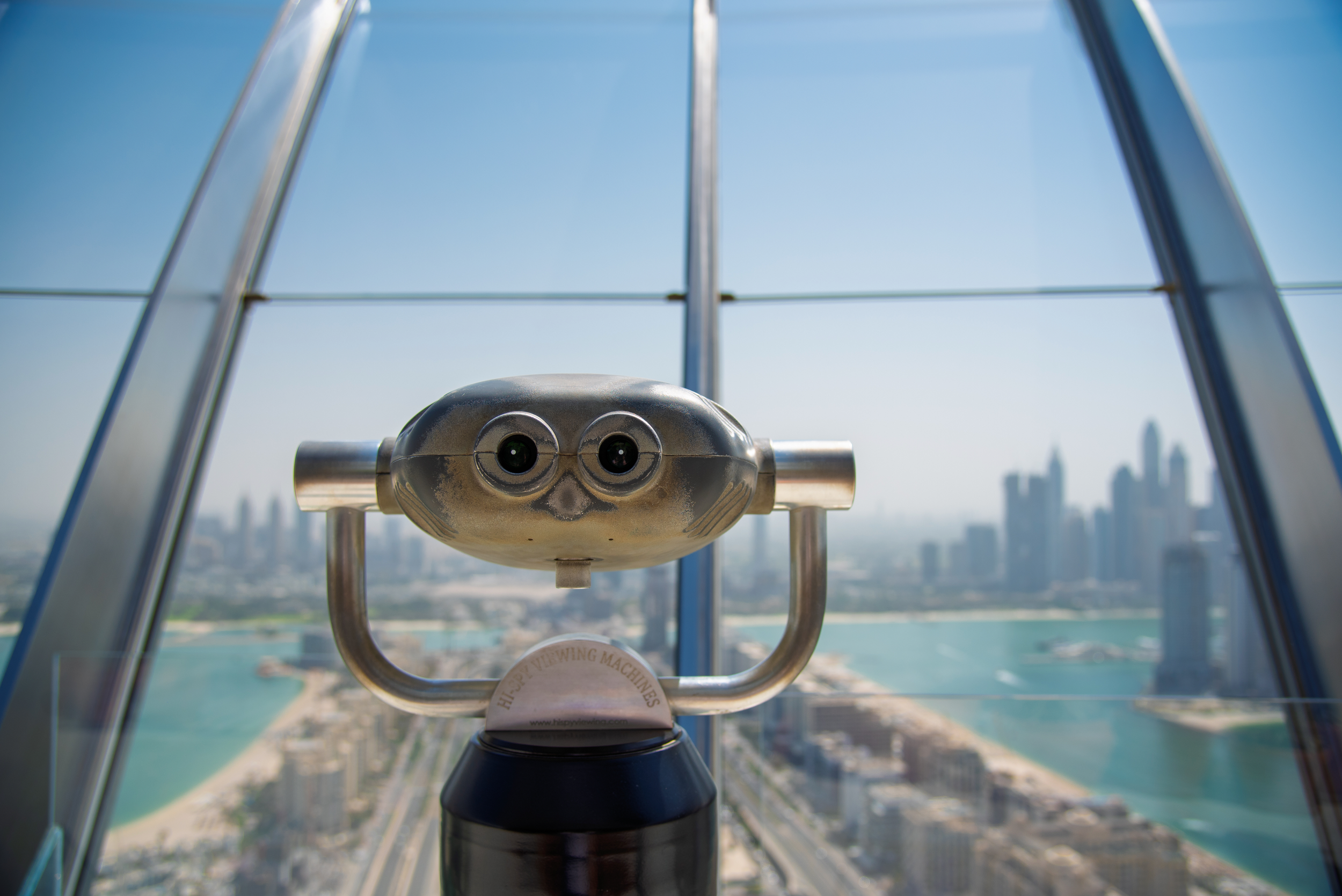 A coin-operated binocular viewer overlooking a city skyline from a high observation deck.