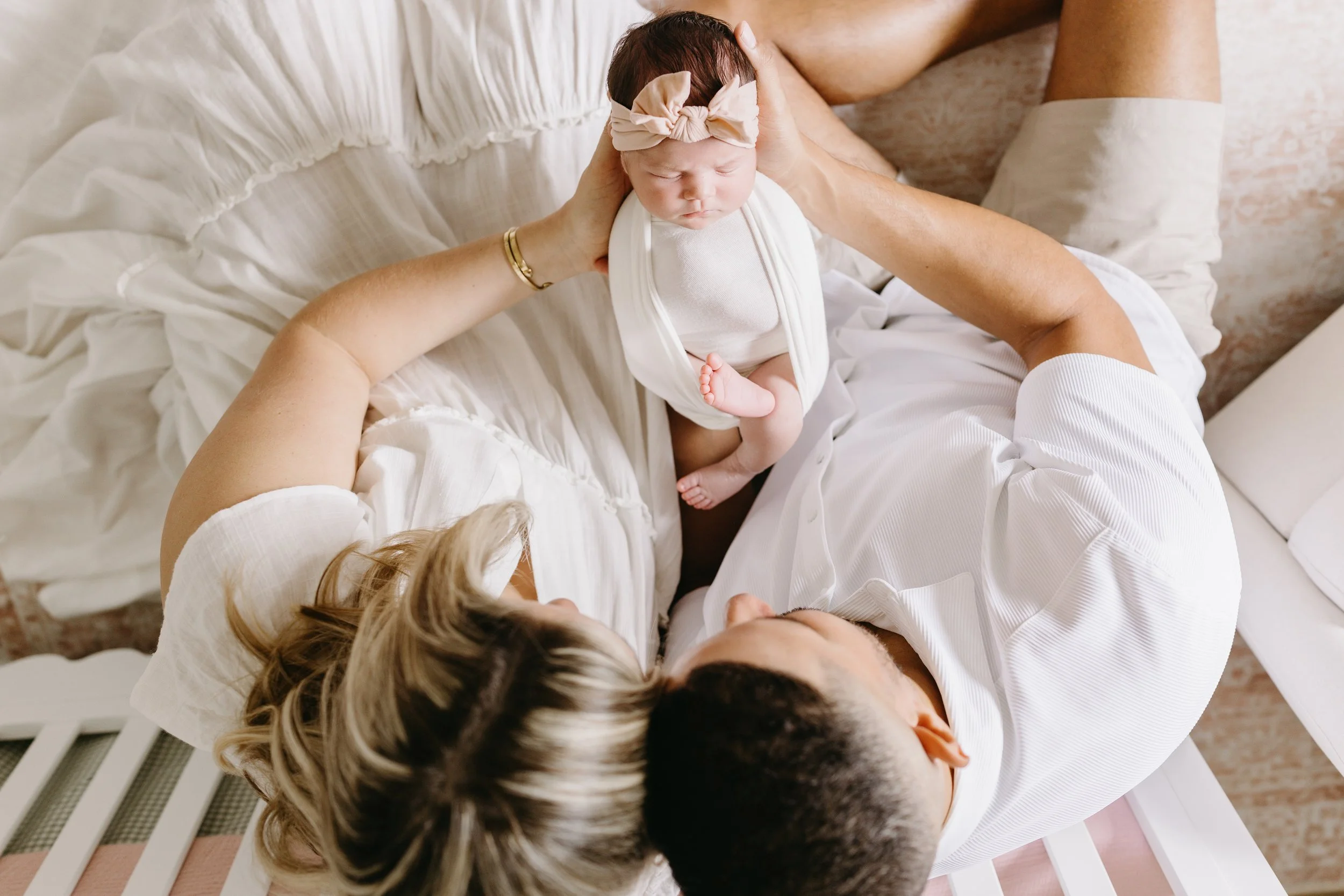 A luxury in-home newborn portrait of mom and dad holding their baby together, captured for a Palm Beach family. Julie James Photography creates elevated, editorial newborn imagery in the comfort of home.