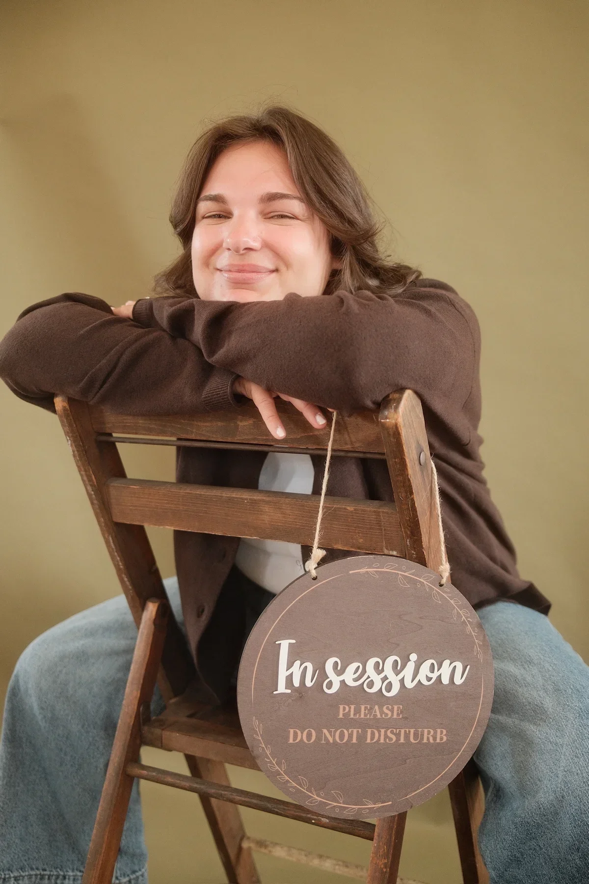 Gabby sitting in her therapy office with an “In Session” sign.