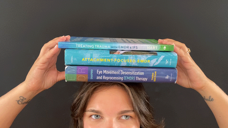 Gabby holding books about EMDR therapy in her therapy practice.