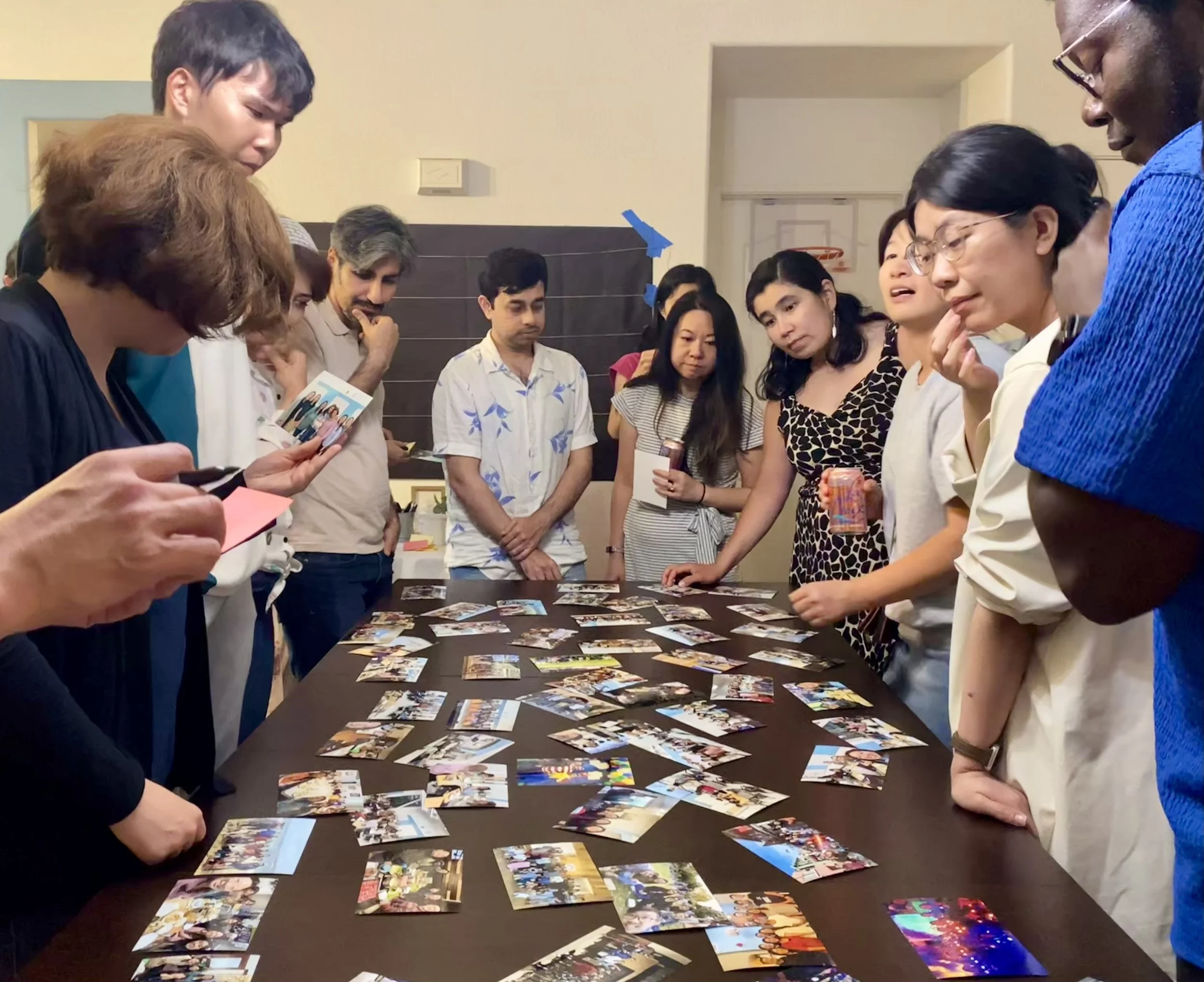 Group of people gathered around a table looking at numerous photographs.