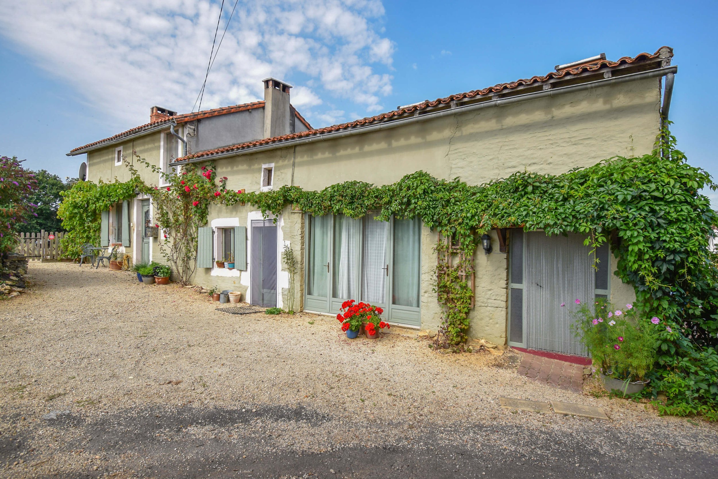 French gîte with large french doors, green plant around the door, and stones leading up to the front door