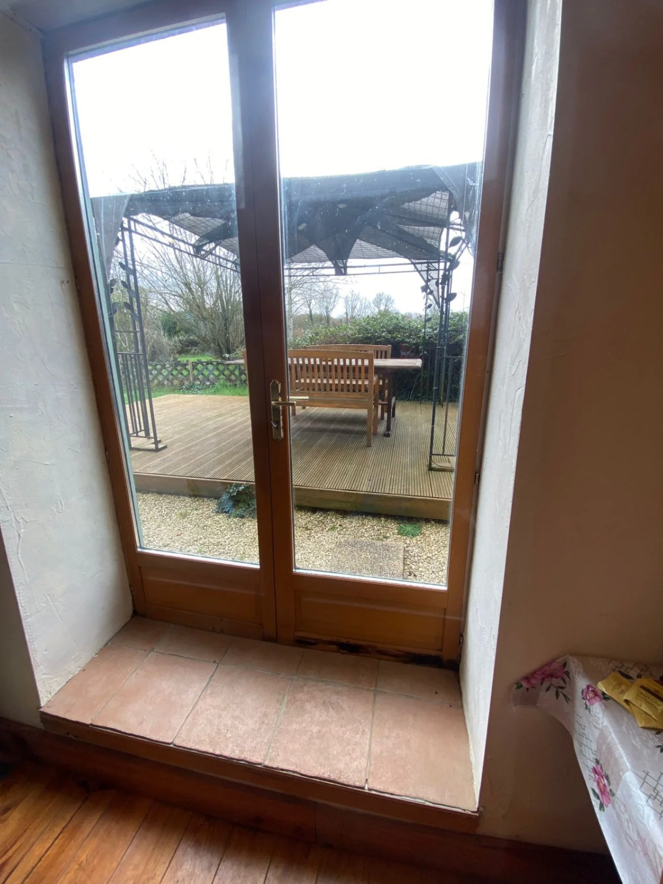 Step up onto a flat surface before double doors that open out onto outside space with step up onto covered decked area