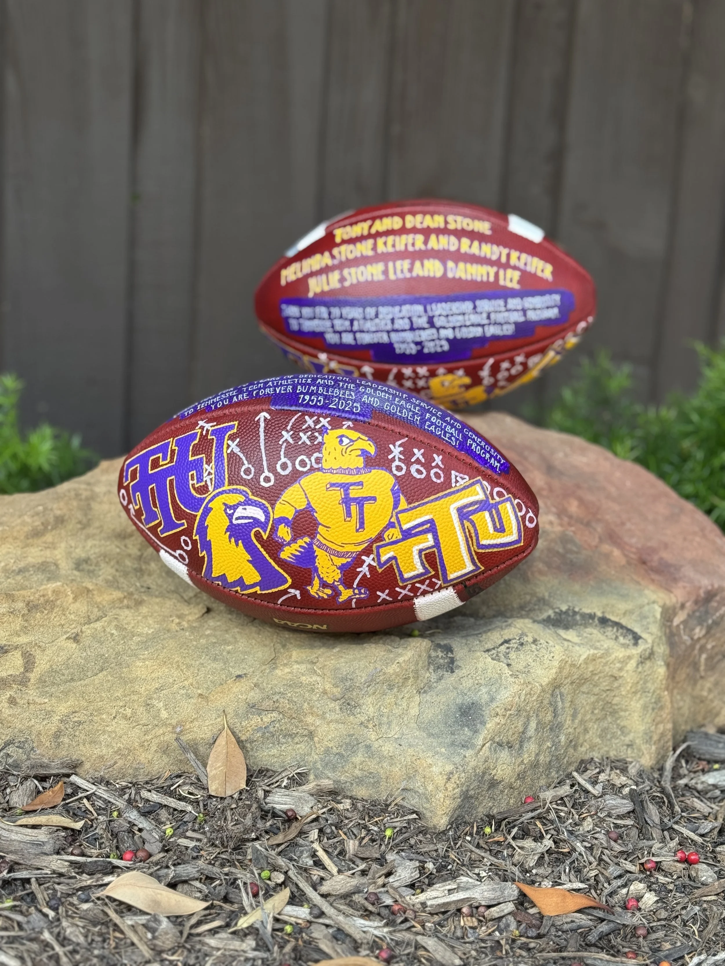Two custom-painted footballs featuring Tennessee Tech colors, mascots and personalized details