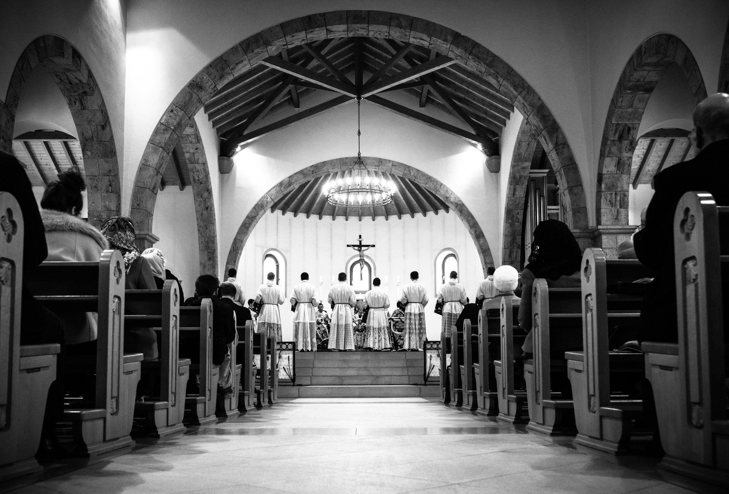A black and white photo of a church service, featuring a group of people standing at the altar.