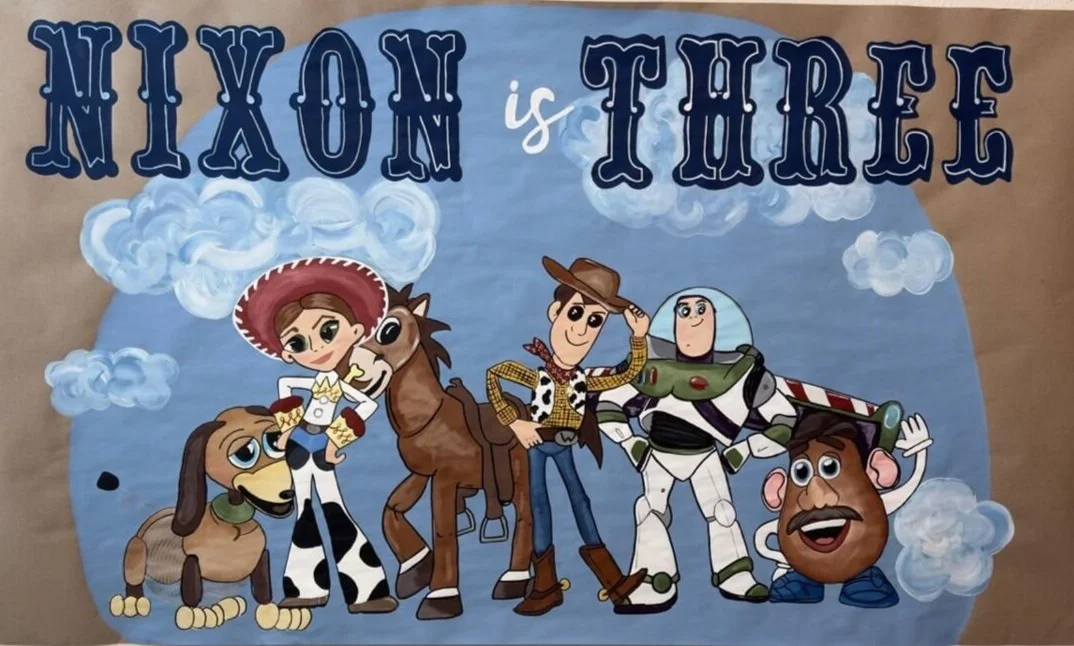 "Nixon is Three" hand-painted banner featuring characters from Toy Story like Woody, Buzz Lightyear, Jessie, and Bullseye.