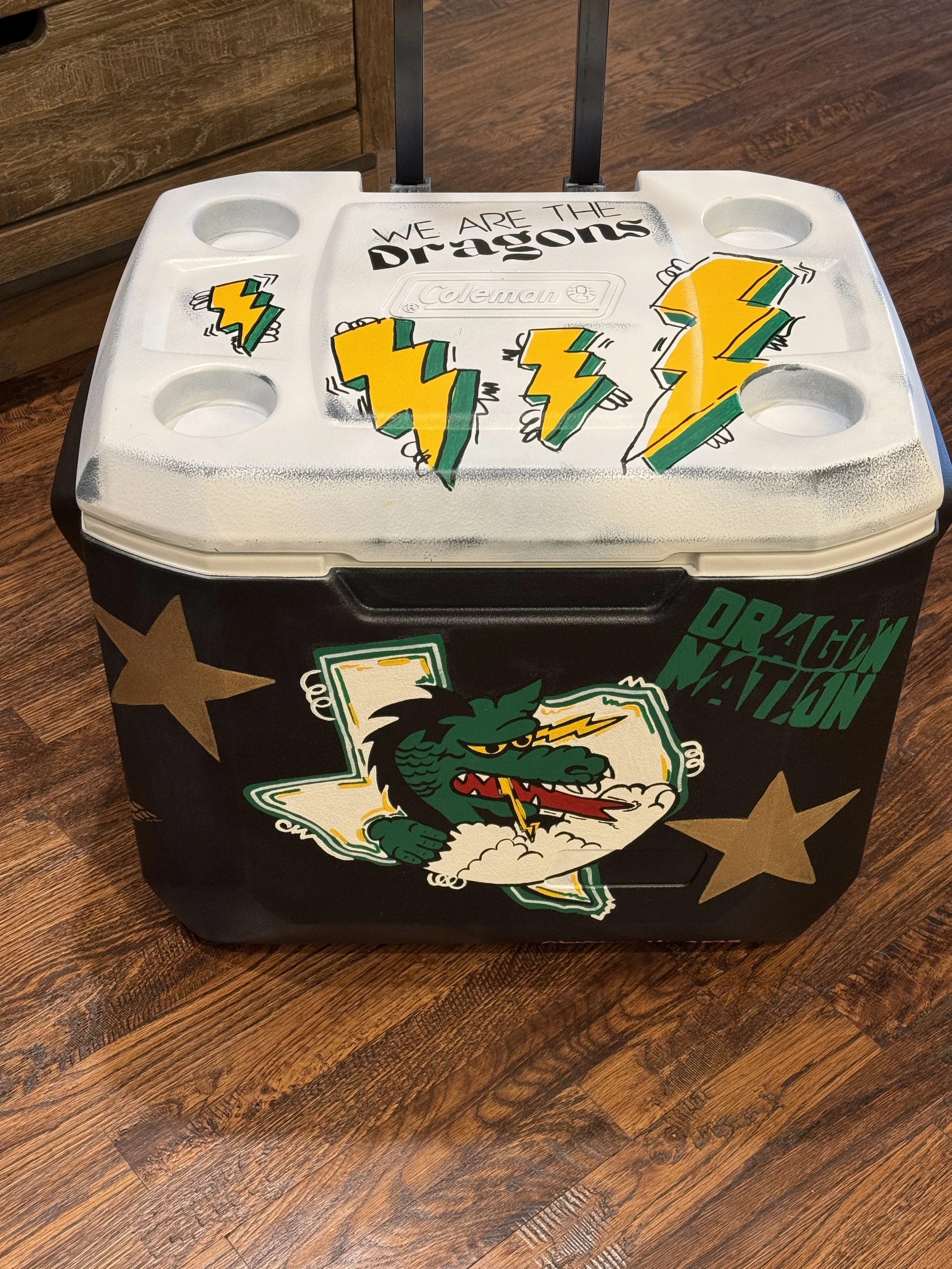 Decorated cooler with "We Are The Dragons" text, yellow and green lightning bolt designs, and a dragon graphic on the front.
