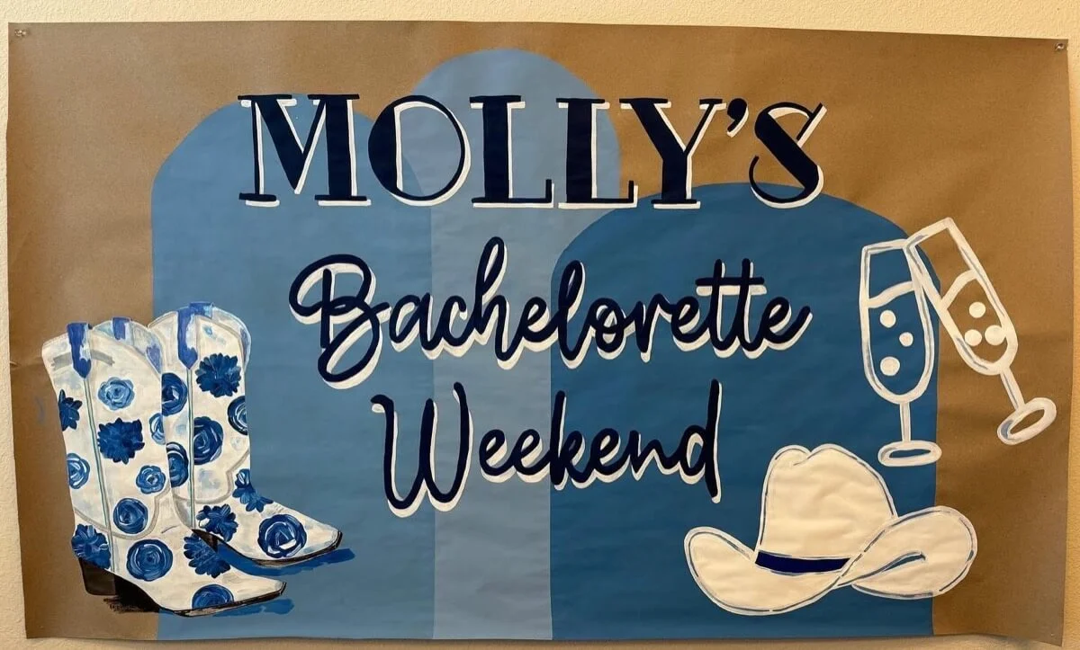 Customisable banner with white cowboy boots, champagne flutes, and text that says, "Molly’s Bachelorette Weekend," on a soft blue and tan background.