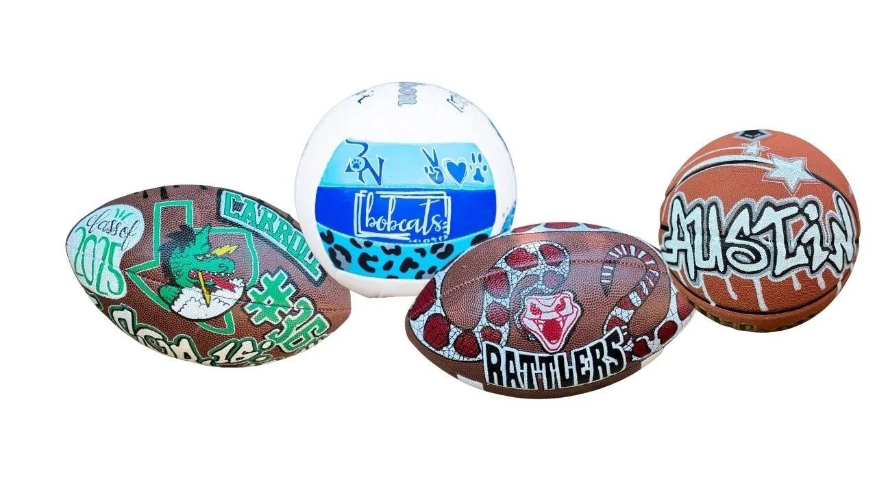 Four custom-designed sports balls: a Carroll Dragons football, a Bobcats volleyball, a Rattlers football, and an "Austin" basketball.