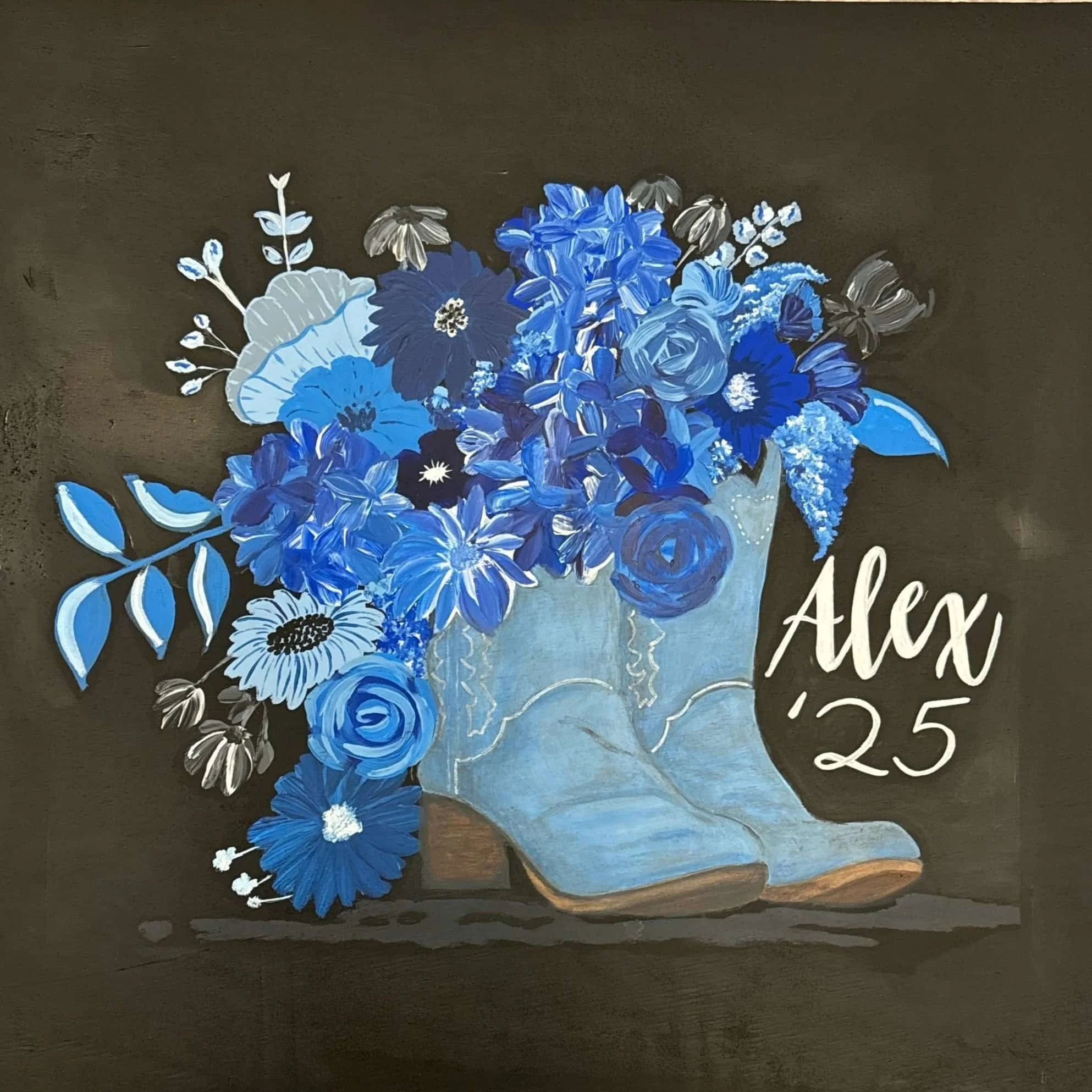 Blue floral bouquet in vintage cowboy boot with the name 'Alex' and the number '25' written beside it.