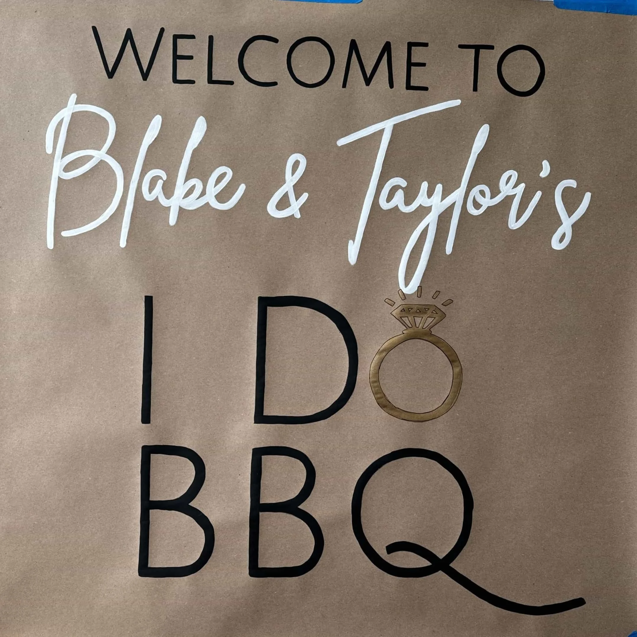 Sign that reads 'Welcome to Blake & Taylor's I Do BBQ' with a gold engagement ring illustration replacing the letter O in 'Do' and as the Q's tail.