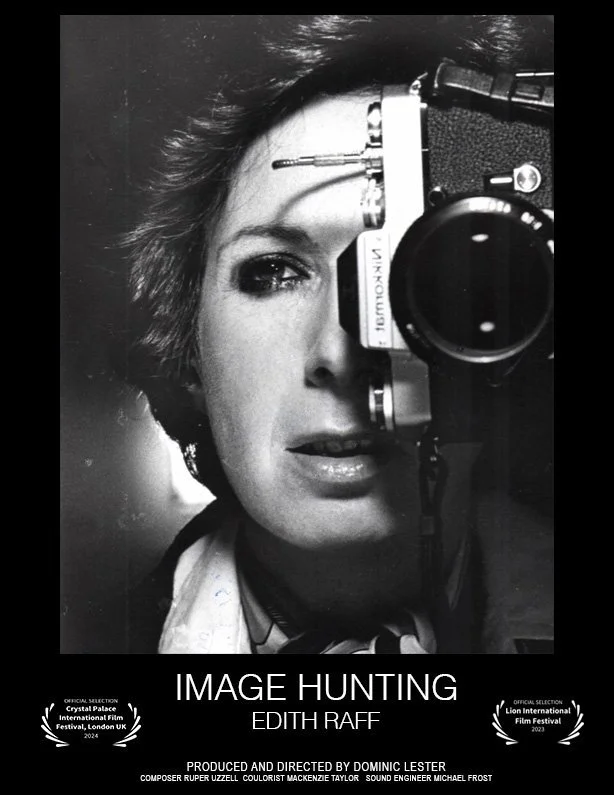 Black and white photo of a woman with short hair, holding a vintage camera close to her face, partially covering one eye, with film festival and awards mention at the bottom.
