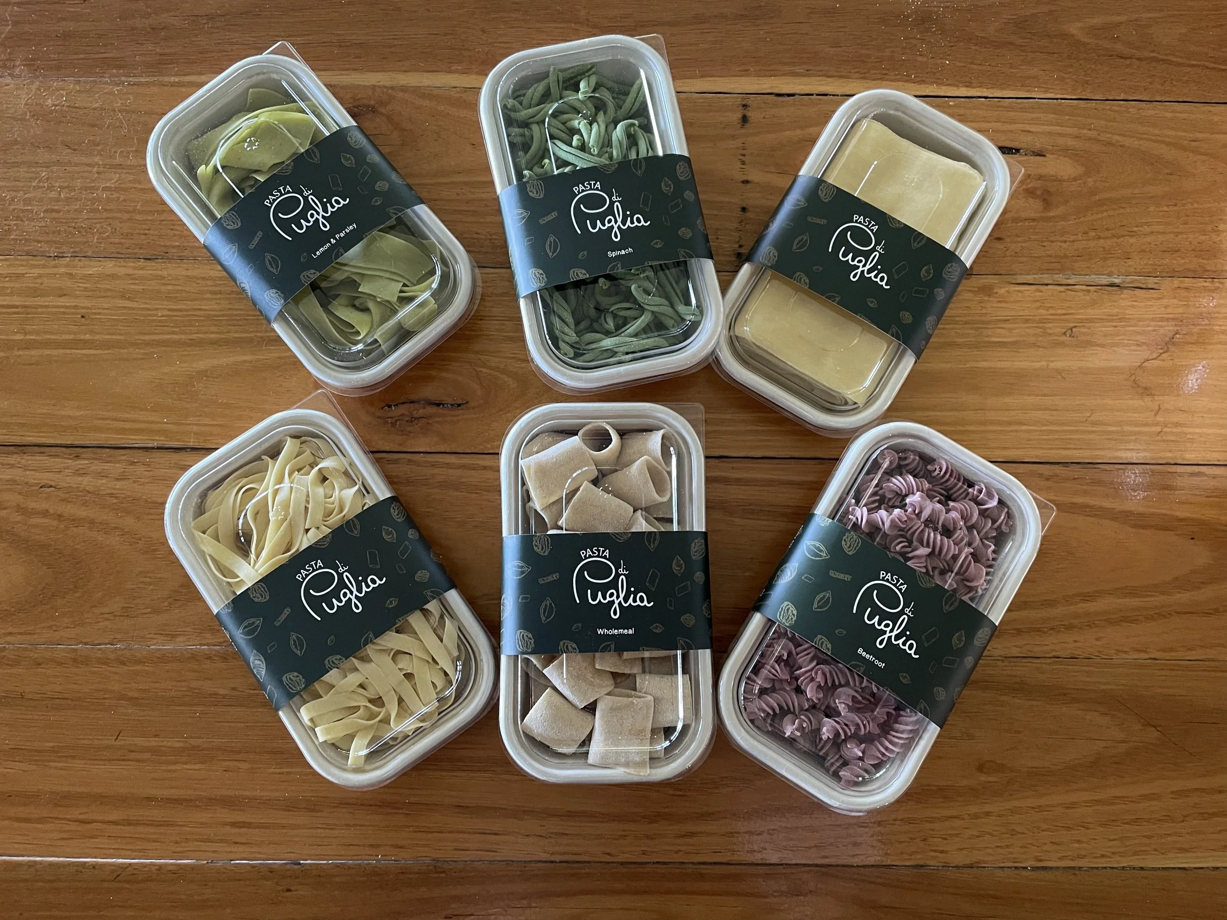 Assorted packages of Pasta di Puglia on a wooden table