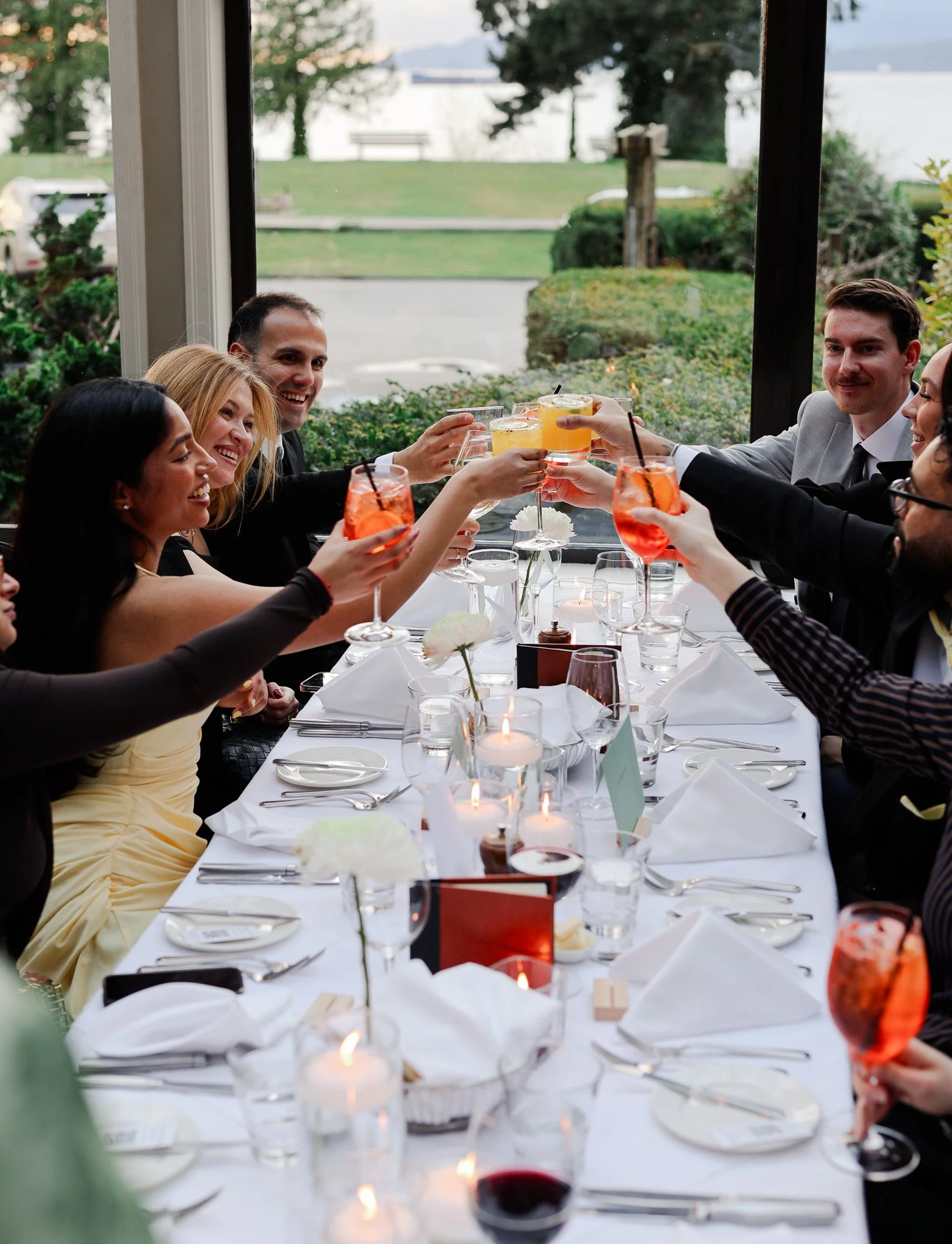 People celebrating and toasting with drinks at a dinner table during a special occasion.