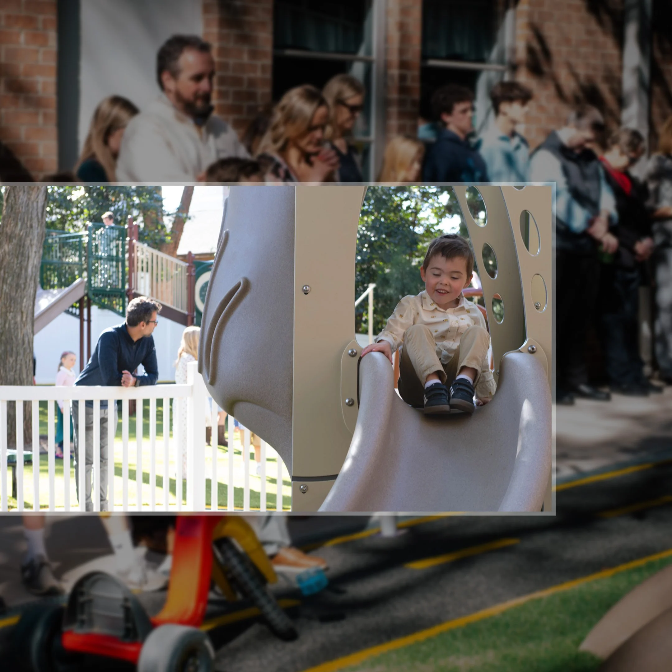 Child playing on a slide at a playground with adults and other children in the background.