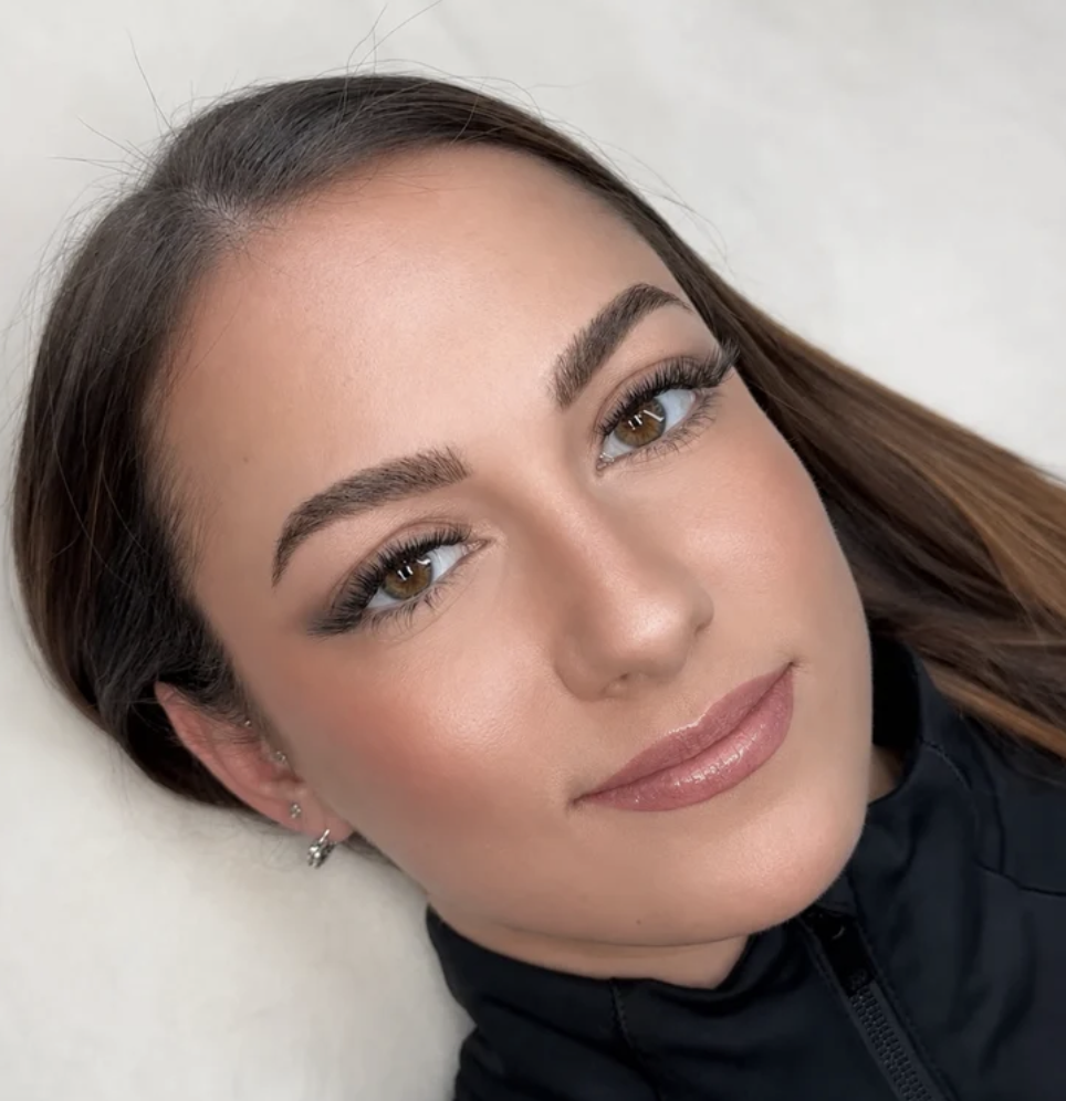 Close-up of a person with dark hair and makeup, looking slightly upwards.