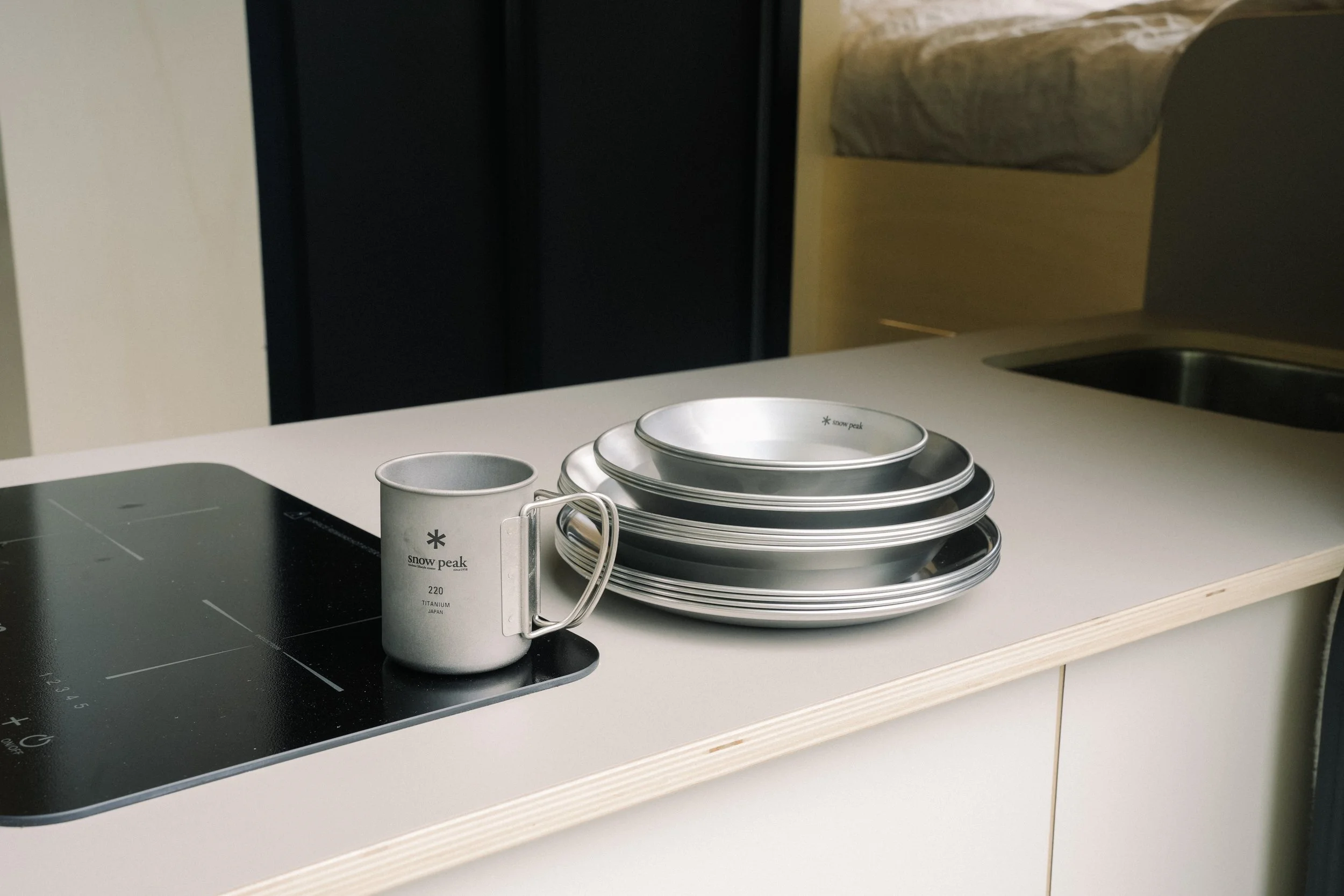 Stack of metal bowls and a mug on a kitchen counter with a black electric stove.
