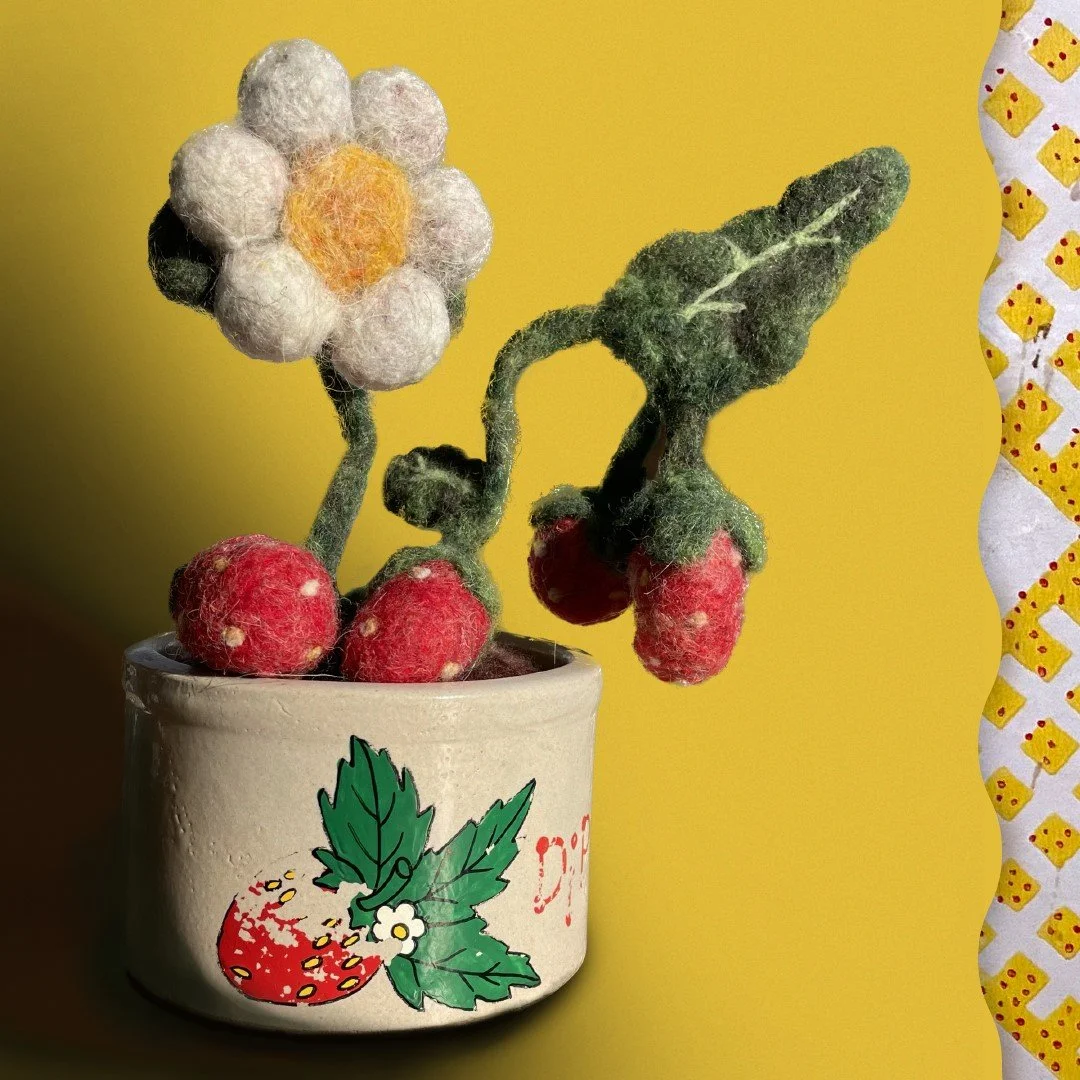 Needle felted strawberry plant in a ceramic bowl with a strawberry on it.