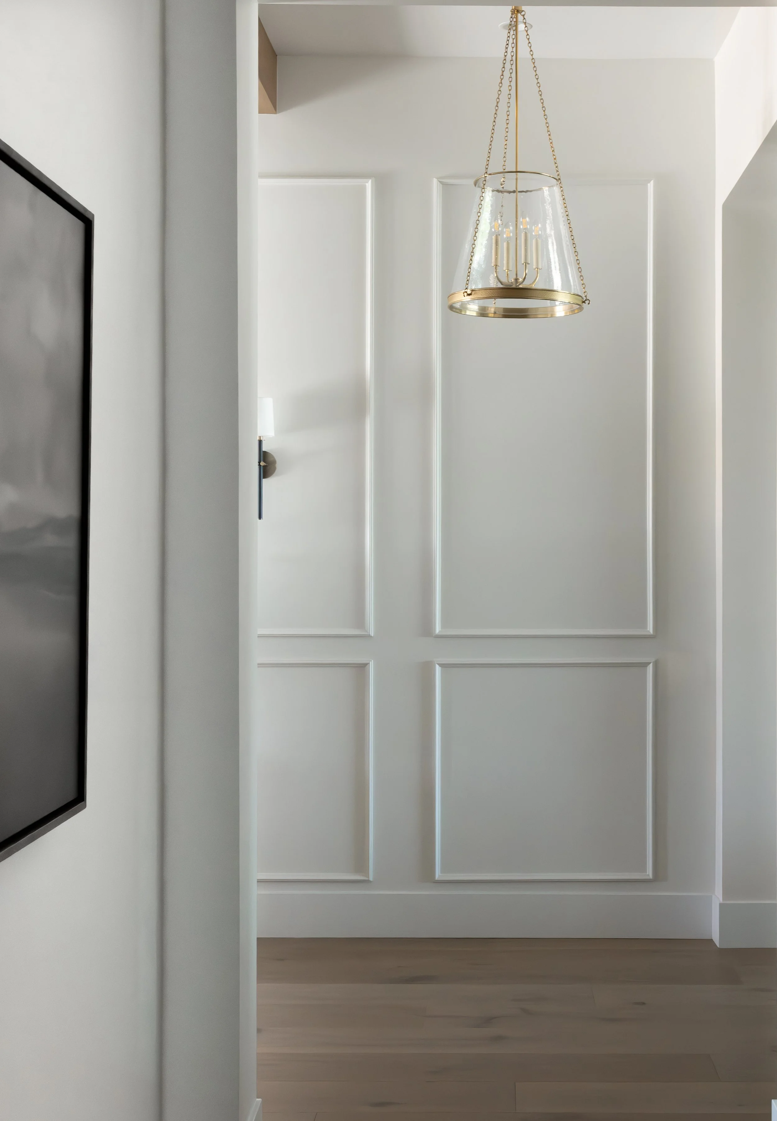 Custom hallway in a Queen Creek, Arizona home featuring decorative wall molding, brass pendant lighting, and timeless organic modern interior design by Wren House Design.