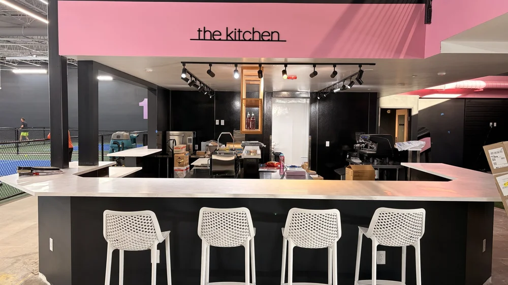 The Kitchen counter at Zero Zero Two under a pink sign.