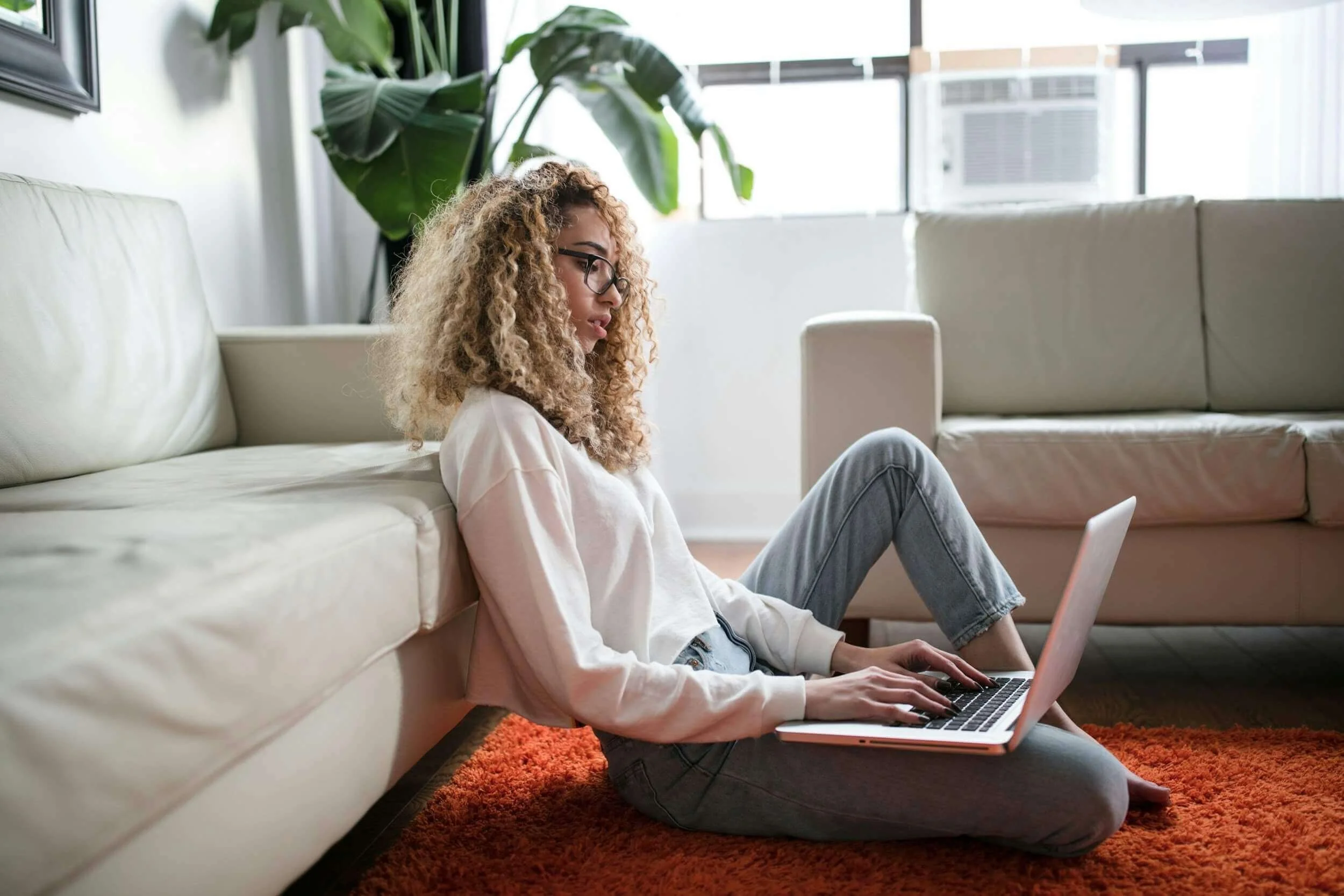 woman sitting on the floor typing on laptop
