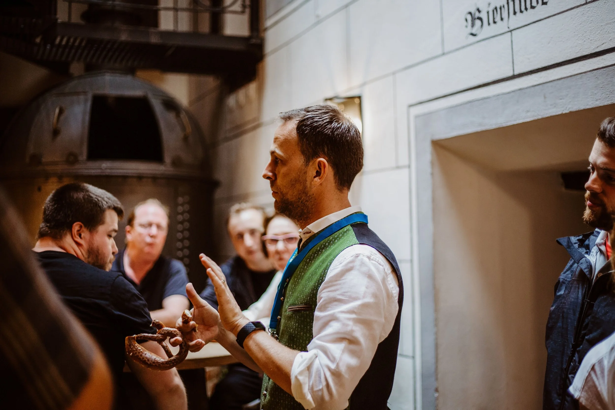 Man in traditional attire performing a demonstration with an octopus in front of a group indoors.