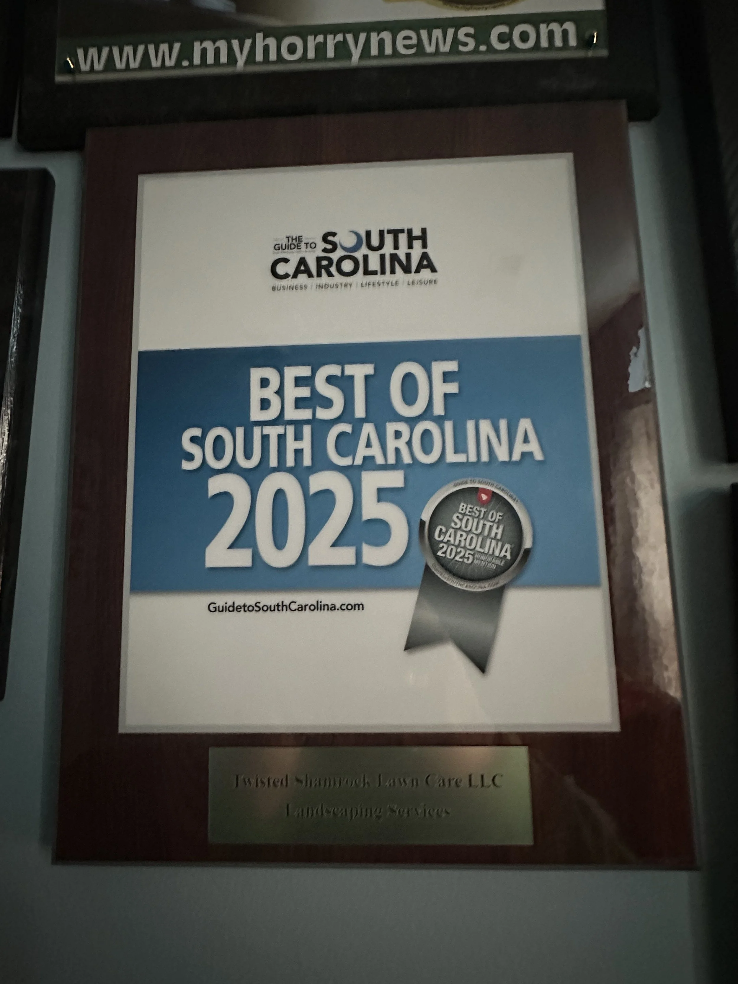 Award plaque titled "Best of South Carolina 2025" from myhorrynews.com with a sticker that says 'Best of South Carolina 2025'. The plaque is from Twisted Shrewd Lawn Care LLC landscaping services.