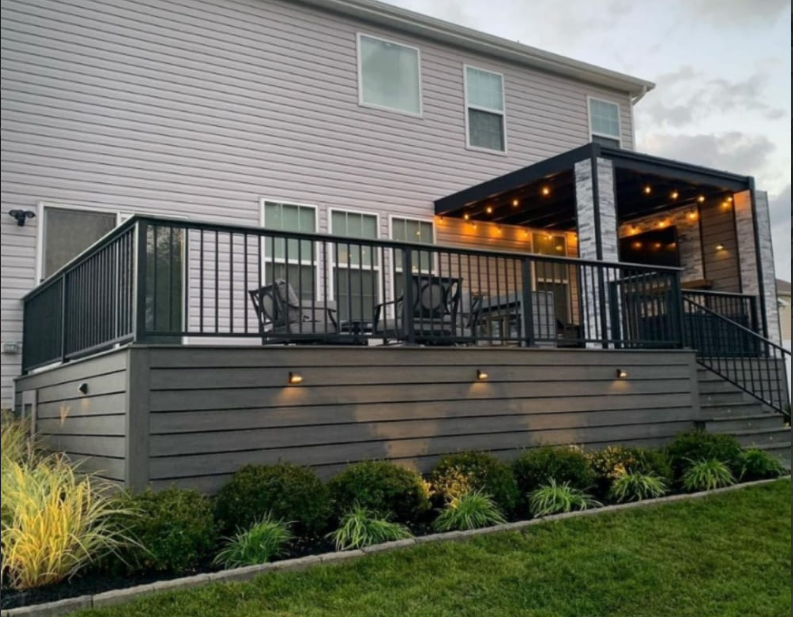 Grey siding on house with back well-lit patio cover - Sunset Decks Patio Cover Builder