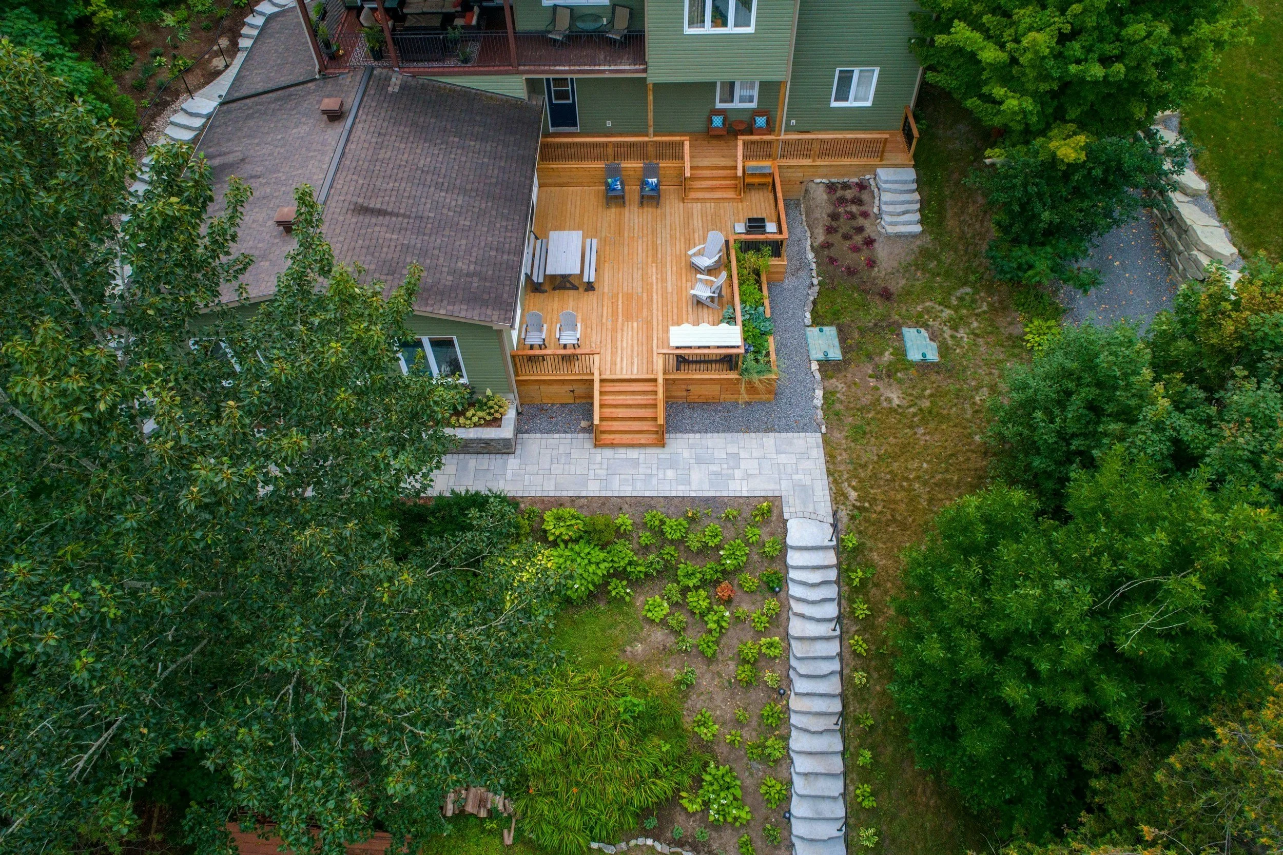Beautiful back yard with green trees and large wooden deck - Sunset Decks - Wood deck builder