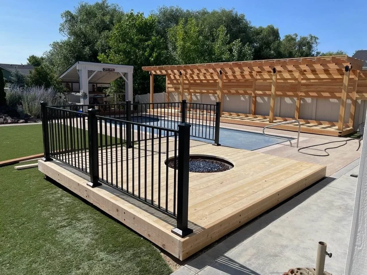 Custom raillings around a firepit outside near a pool and a pergola by Sunset Decks Idaho