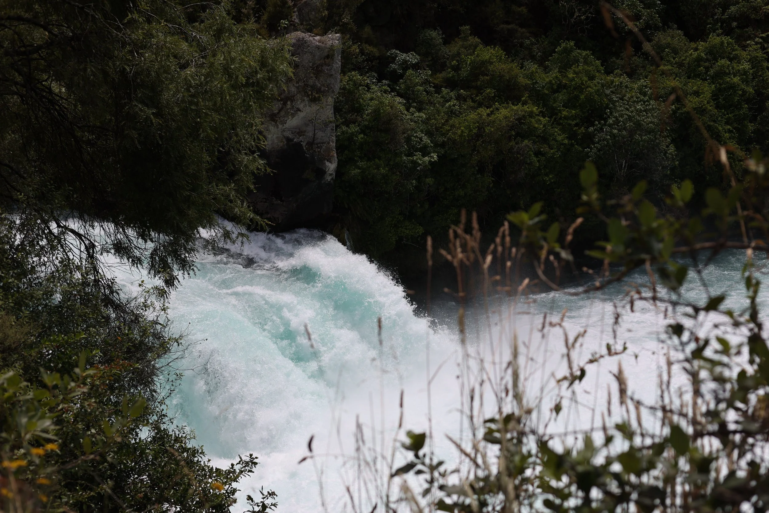 Waterfall surrounded by lush green foliage, with rushing water cascading over rocks.