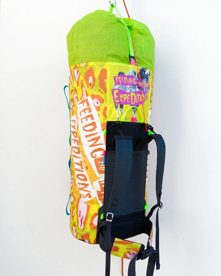 Colorful backpack with text and graphics hanging against a plain white background.