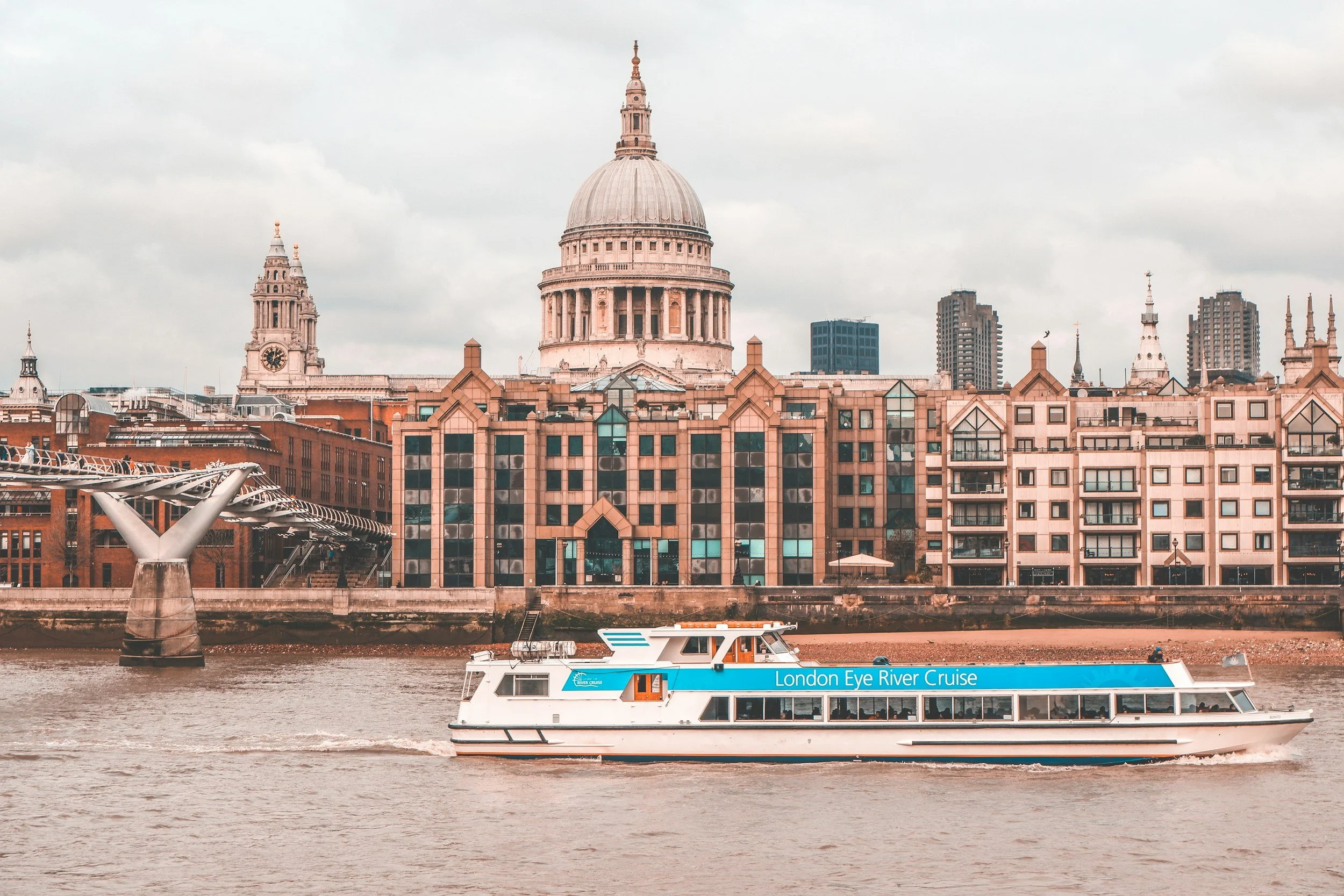 Tour boat on River Thames near historic buildings, including St. Paul's Cathedral, in London.