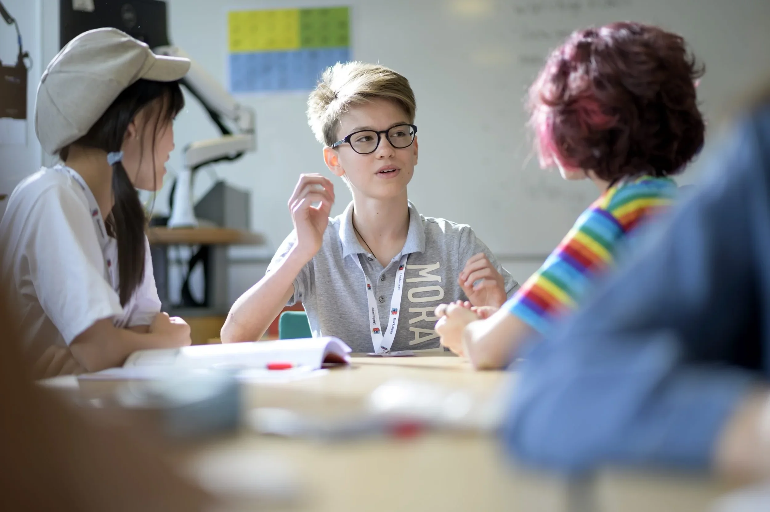 Young boys and girls sitting at a table engaging in a discussion or game in a classroom.