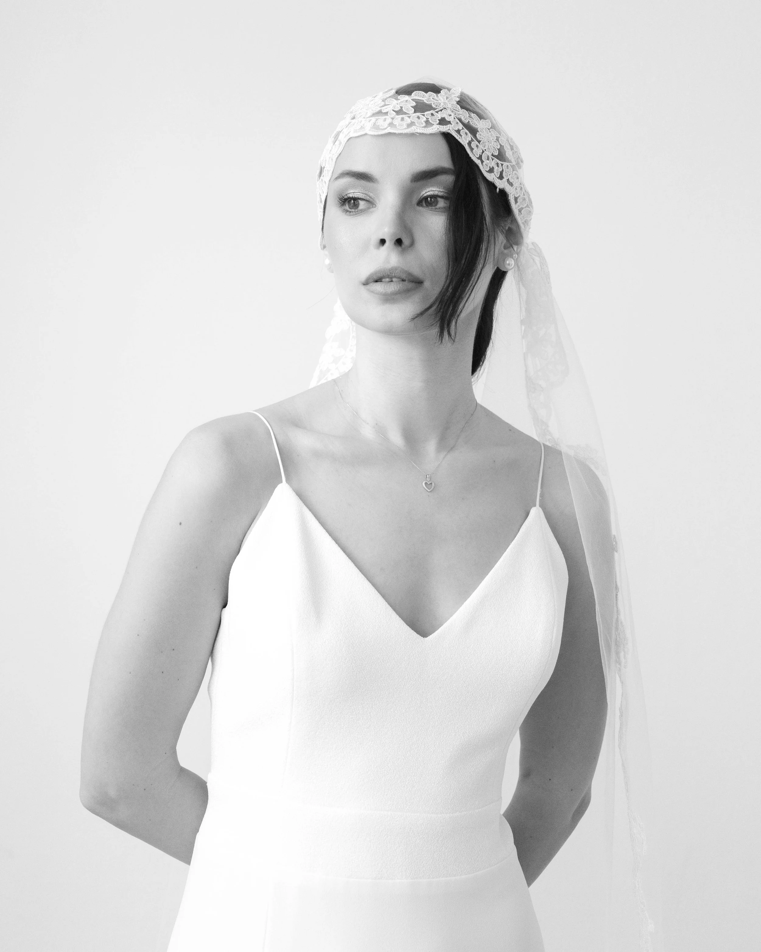 Retrato en blanco y negro de una mujer con vestido blanco y velo de encaje.