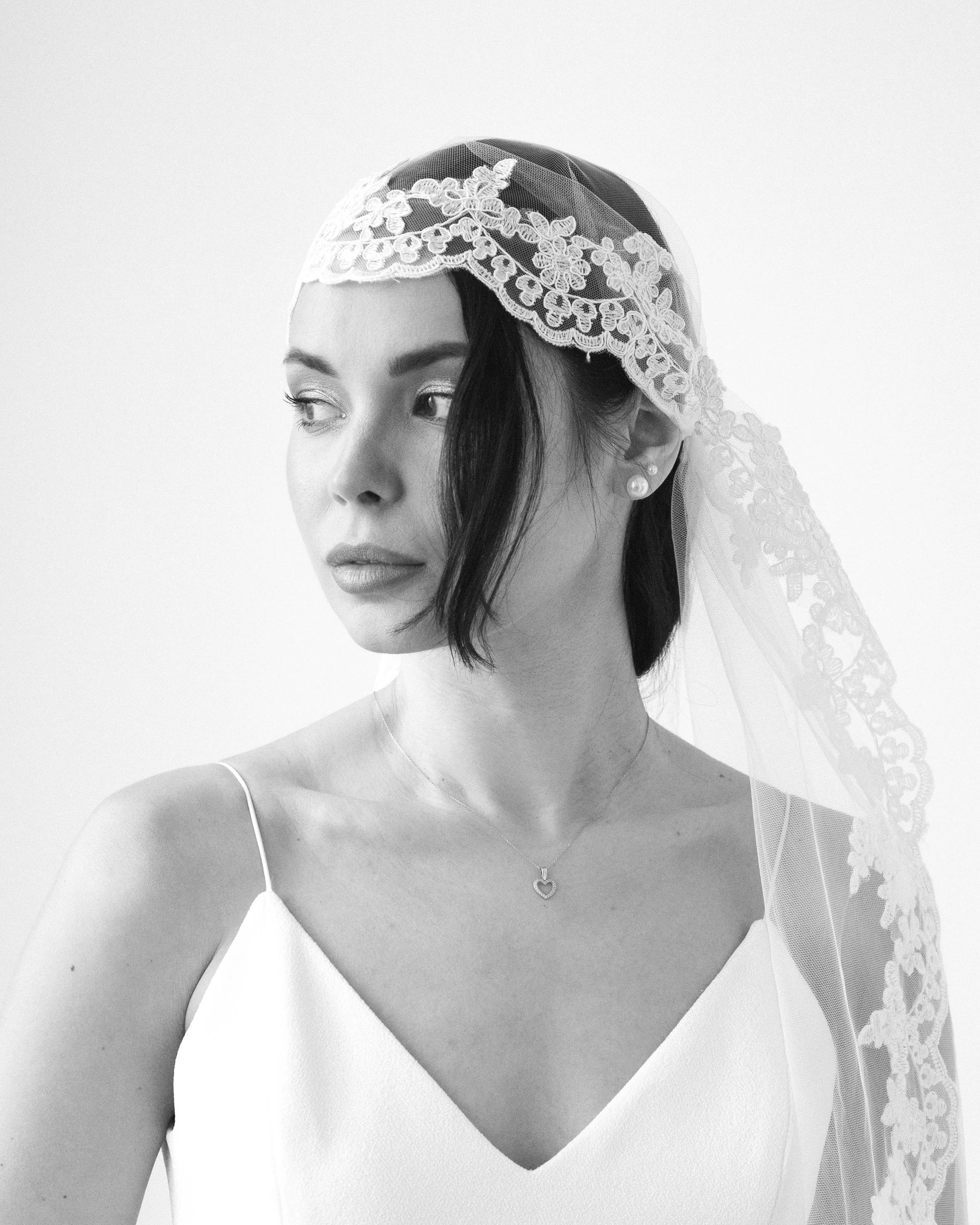 Retrato en blanco y negro de una mujer con vestido de novia y velo, mirando hacia la izquierda.