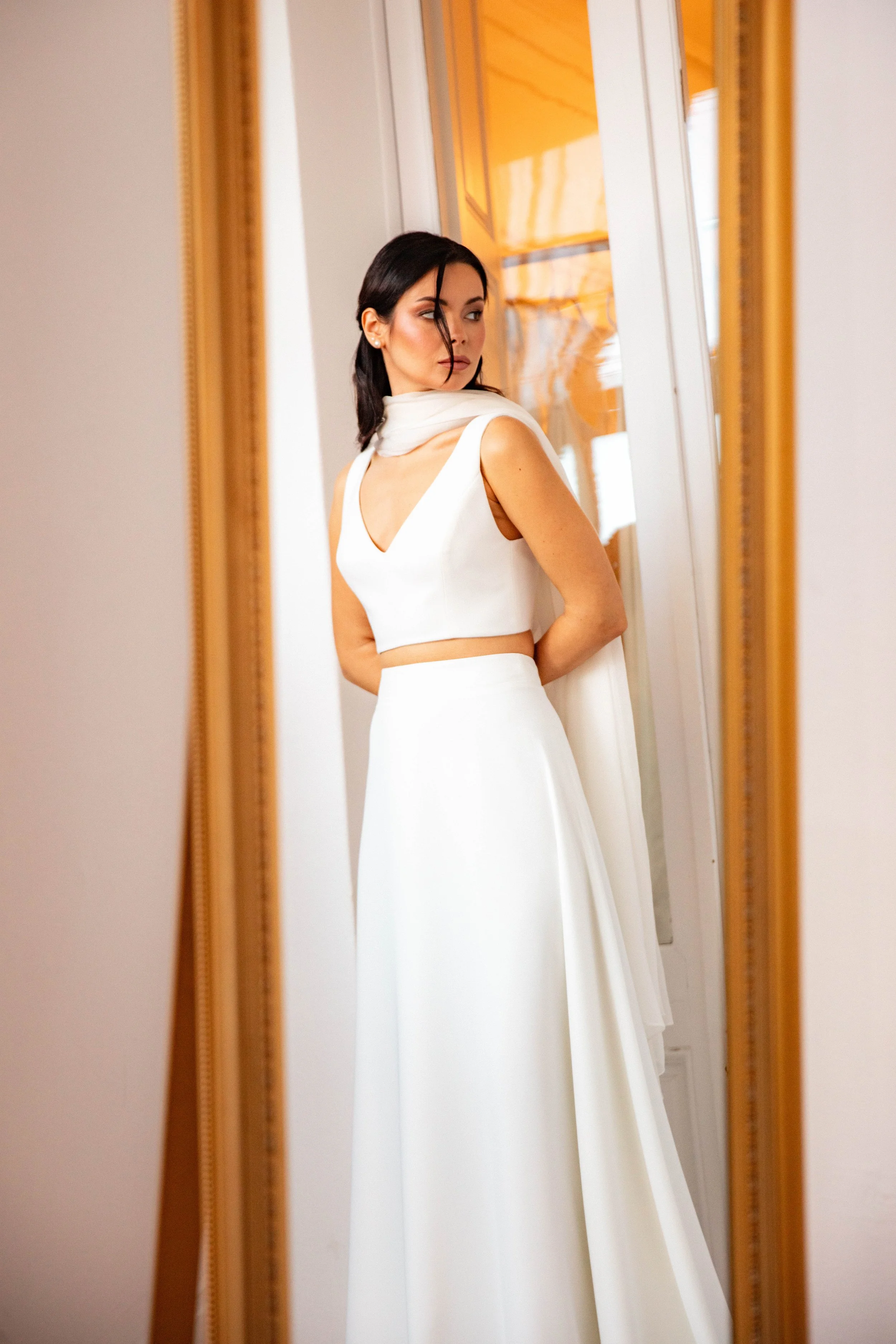 Mujer en vestido de novia mirando por detrás en un espejo.