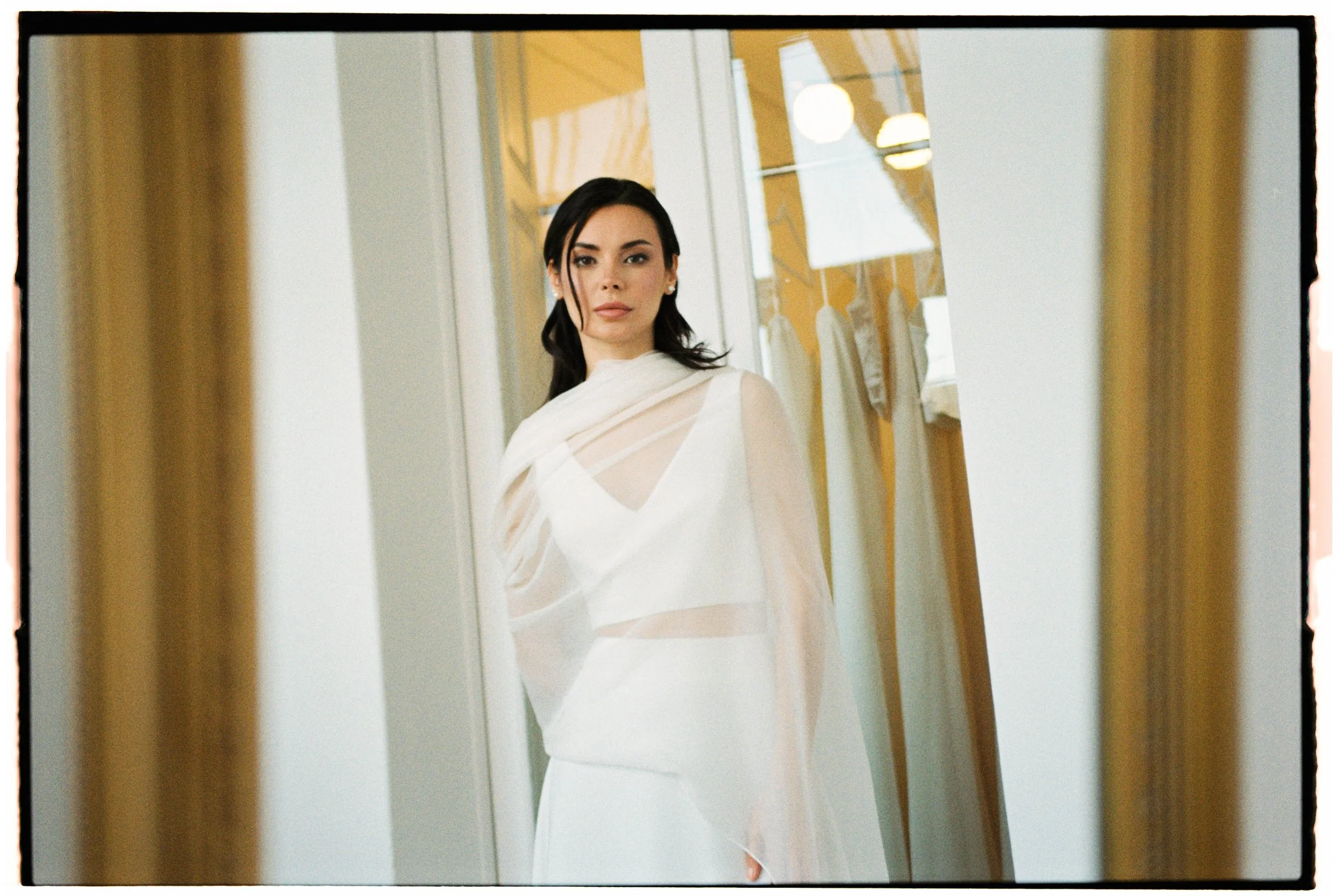 Mujer con vestido blanco en vestidor frente a espejo.
